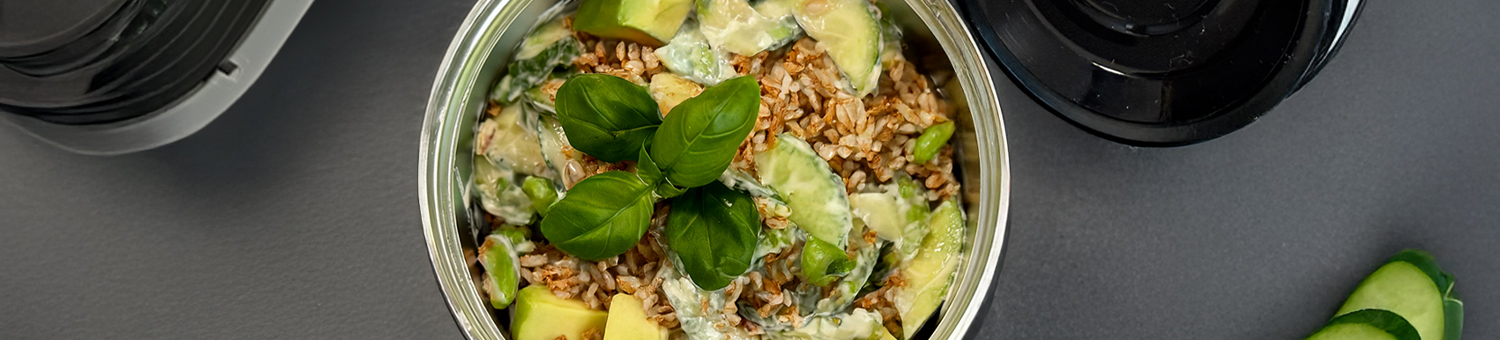 Runde Lunchbox mit Dinkelsalat, Avocado und Basilikum