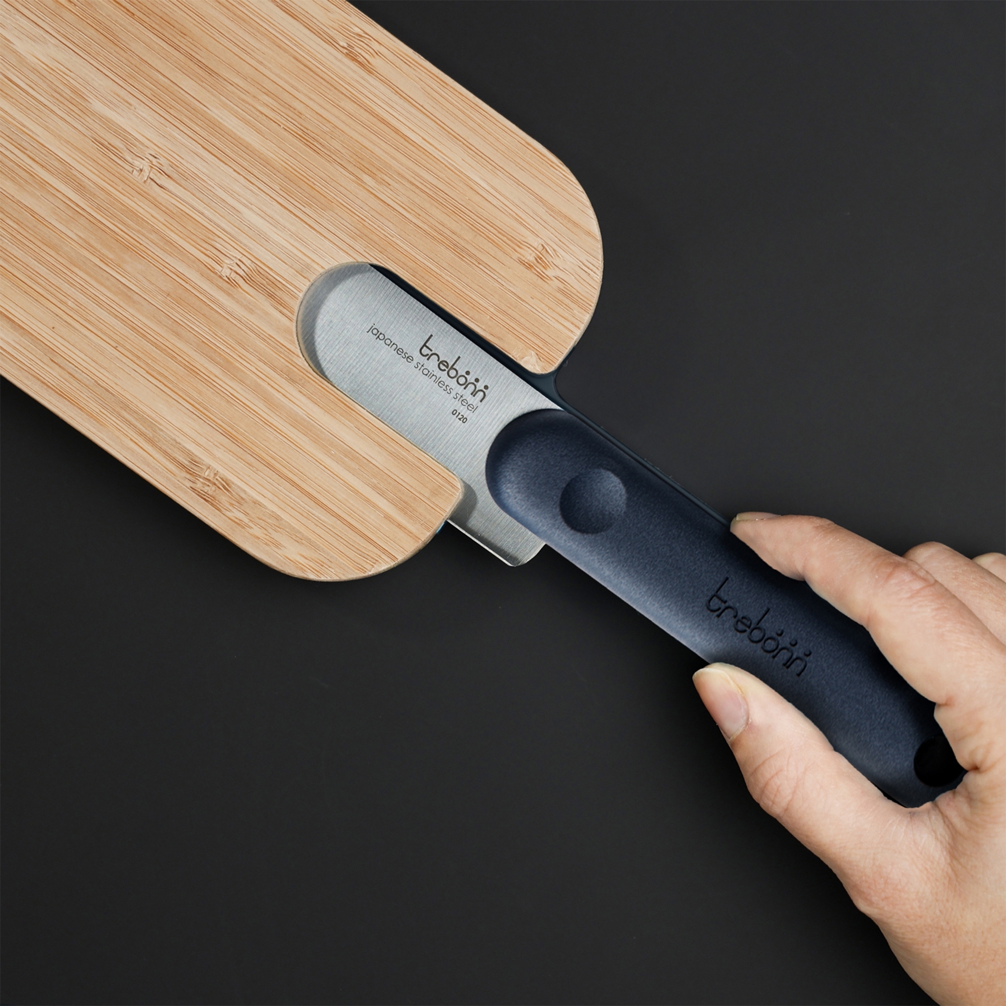 Hand with knife in bamboo cutting board