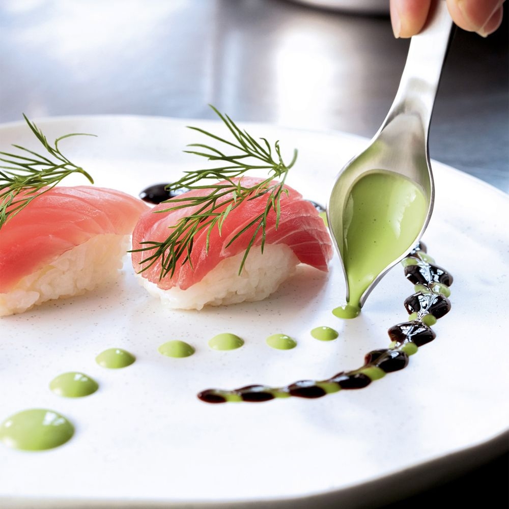 Two nigiri sushi artfully garnished with green sauce