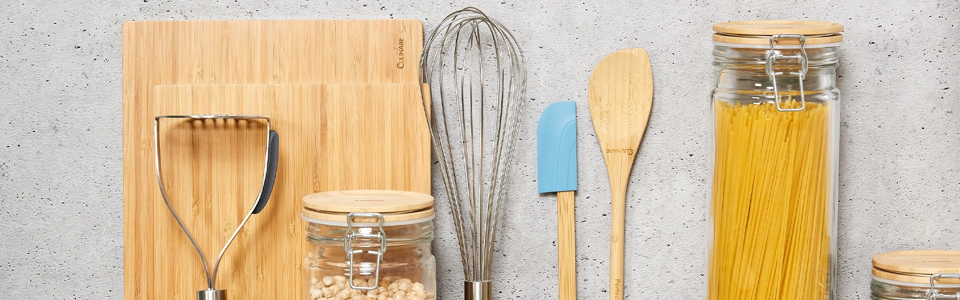 Row of bamboo kitchen utensils with glass storage jars