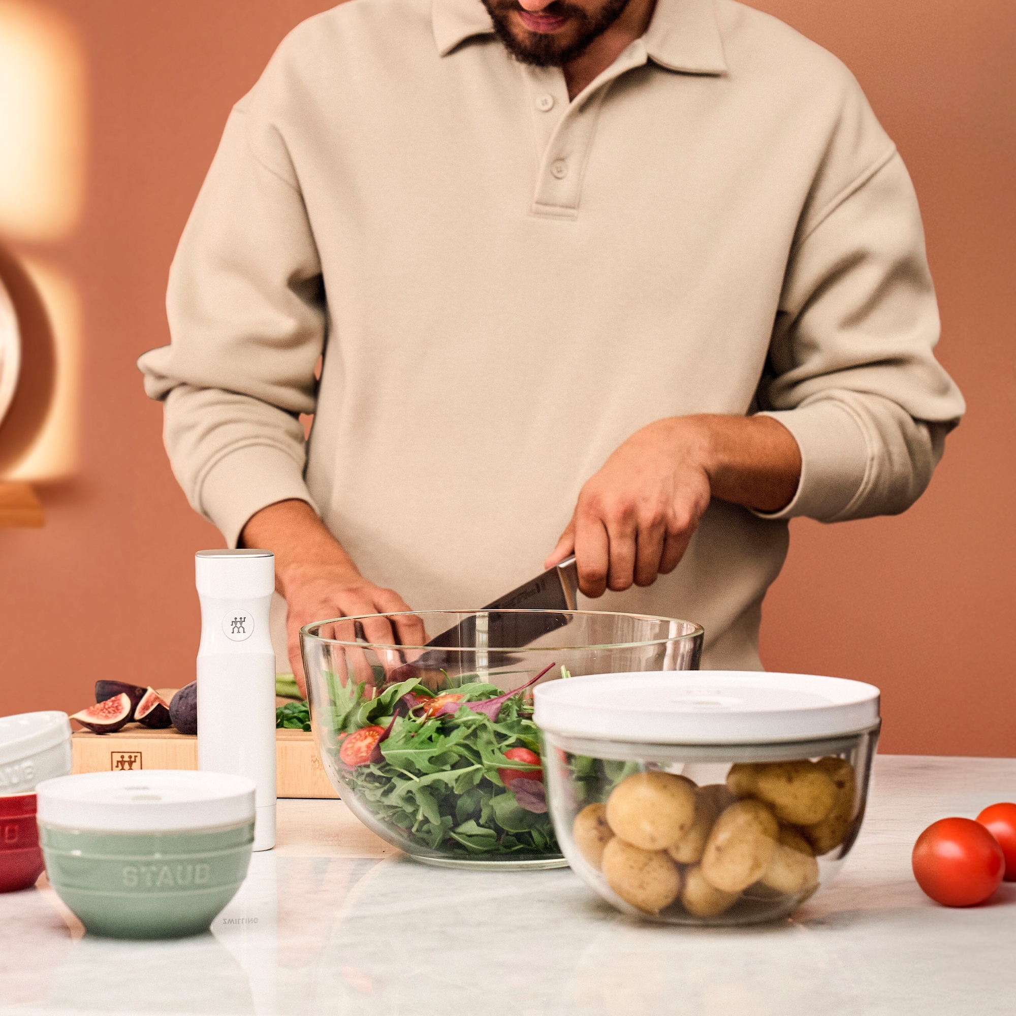 Mann schneidet Salat in großer Glasschüssel