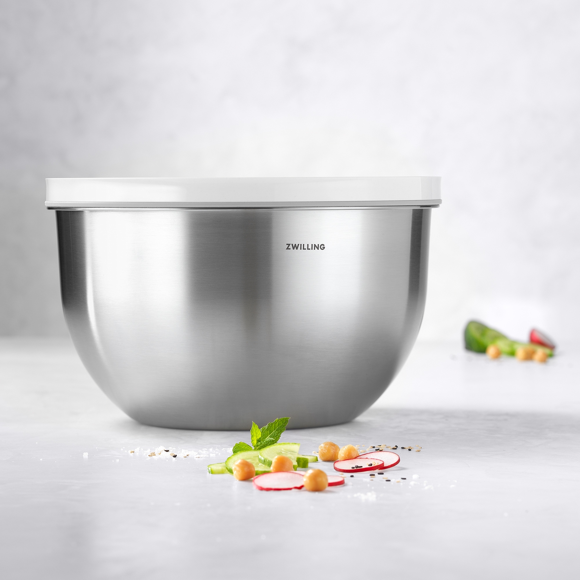 Stainless steel bowl with white lid and fresh vegetables