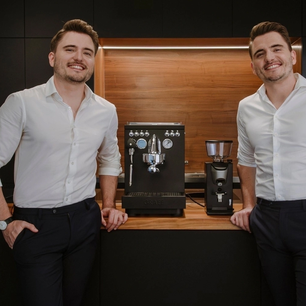 Two men presenting espresso machine and coffee grinder