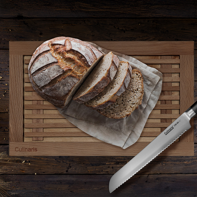 Bread knife beside sliced loaf on wooden board