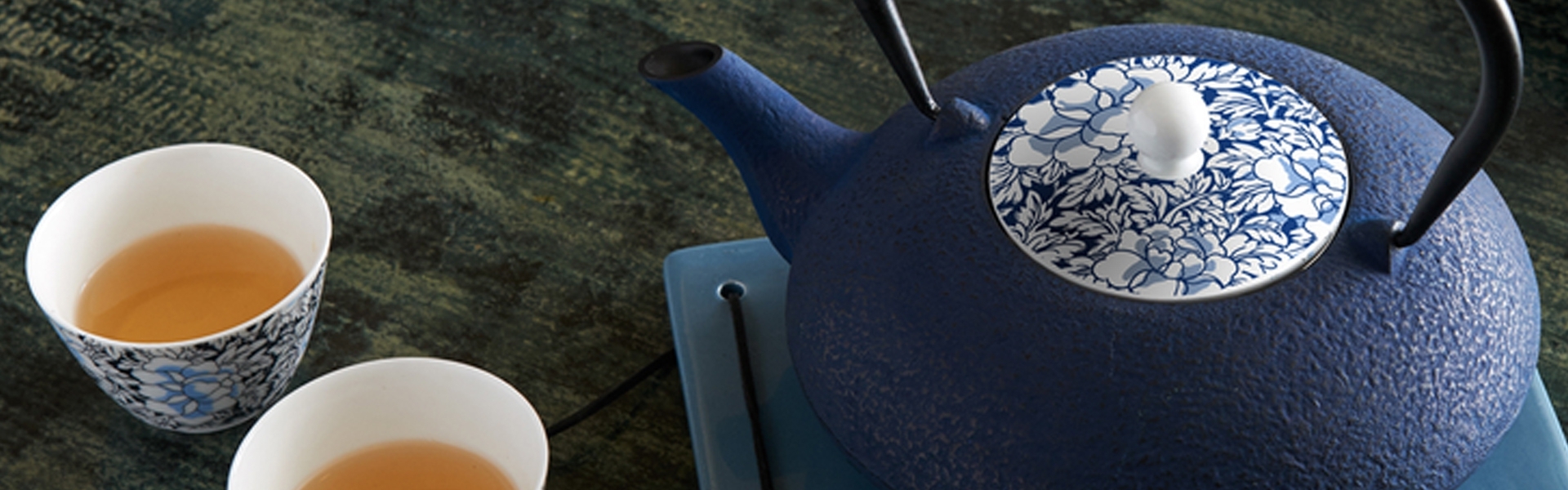 Blue cast iron pot with tea and two cups