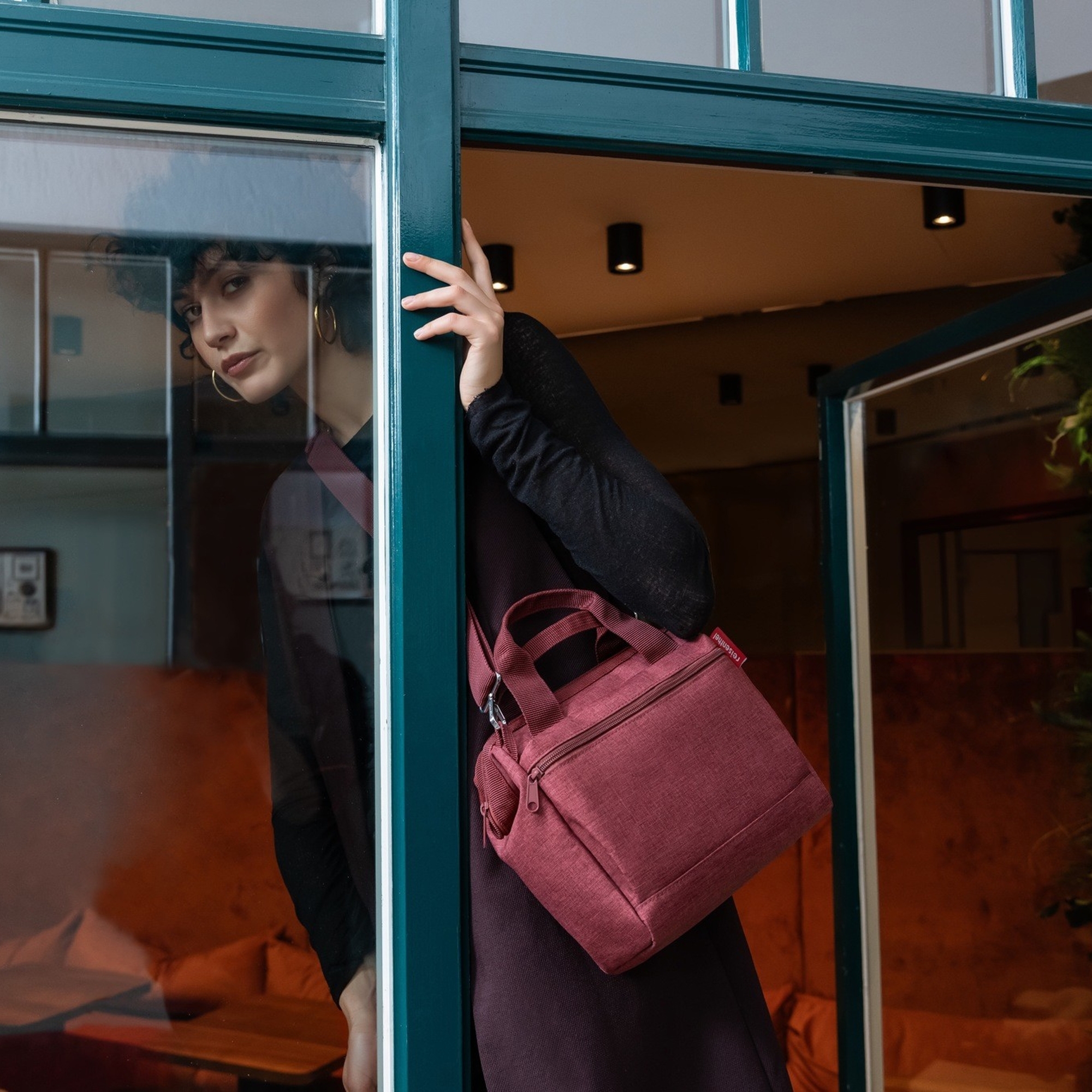 Woman with burgundy shoulder bag at glass door
