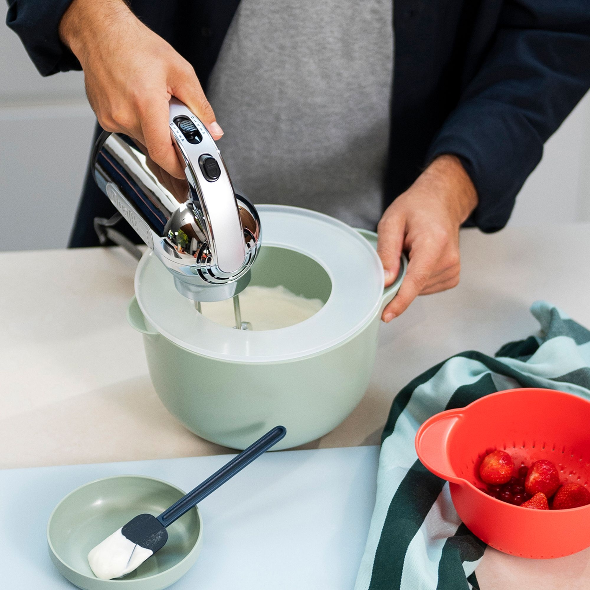 Person nutzt Handmixer in Schüssel beim Backen
