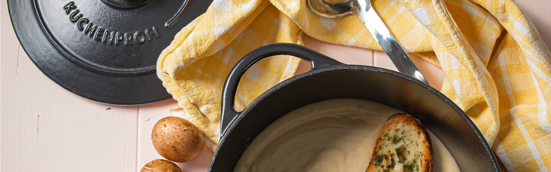 Open cast iron pot with soup, bread and lid