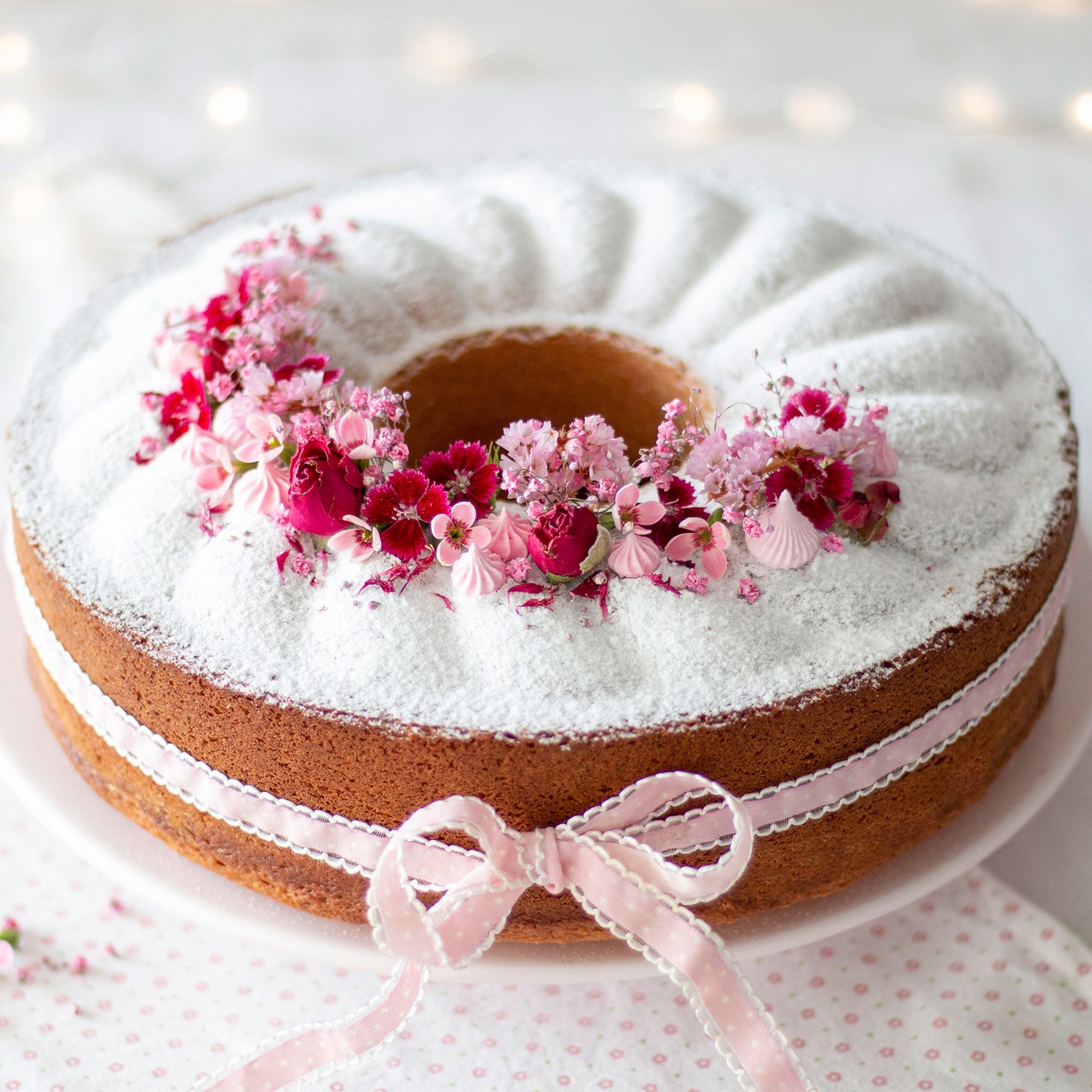 Runder Gugelhupf mit rosa Blütendekor und Schleife