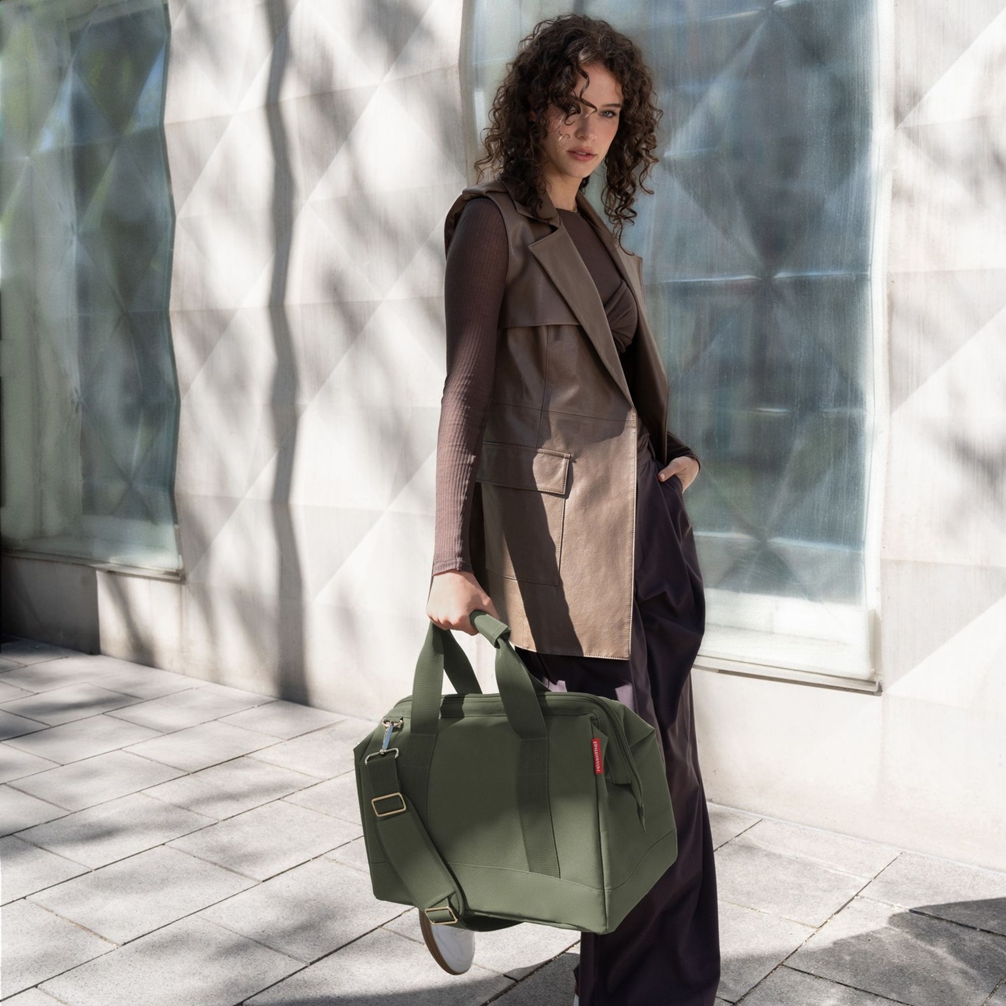 Woman carrying olive green weekender bag outdoors