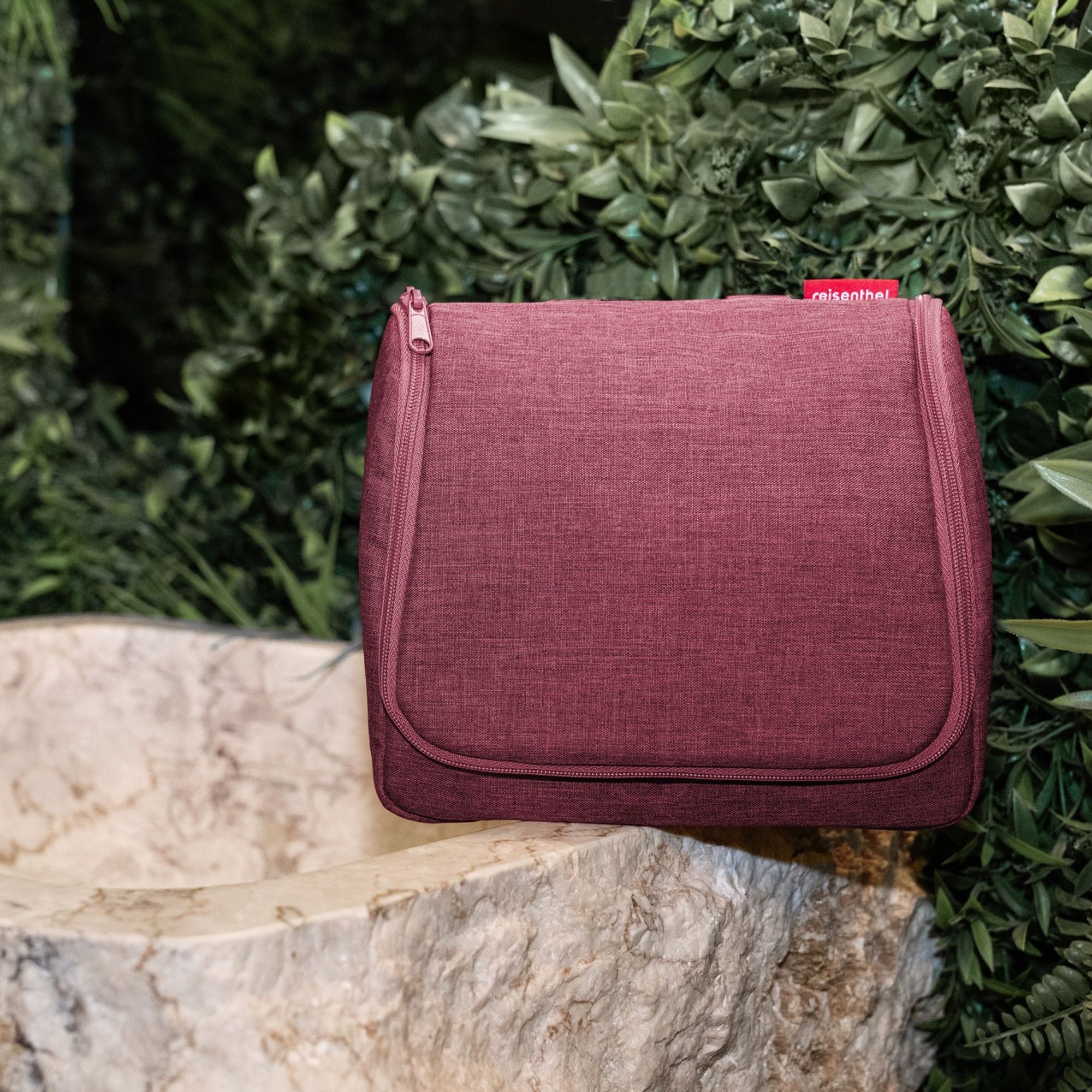 Burgundy fabric toiletry bag on marble sink