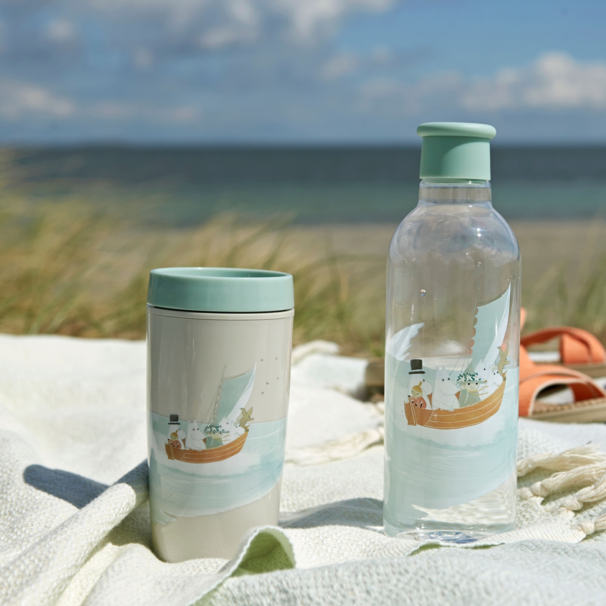 Moomin water bottle and travel mug on beach