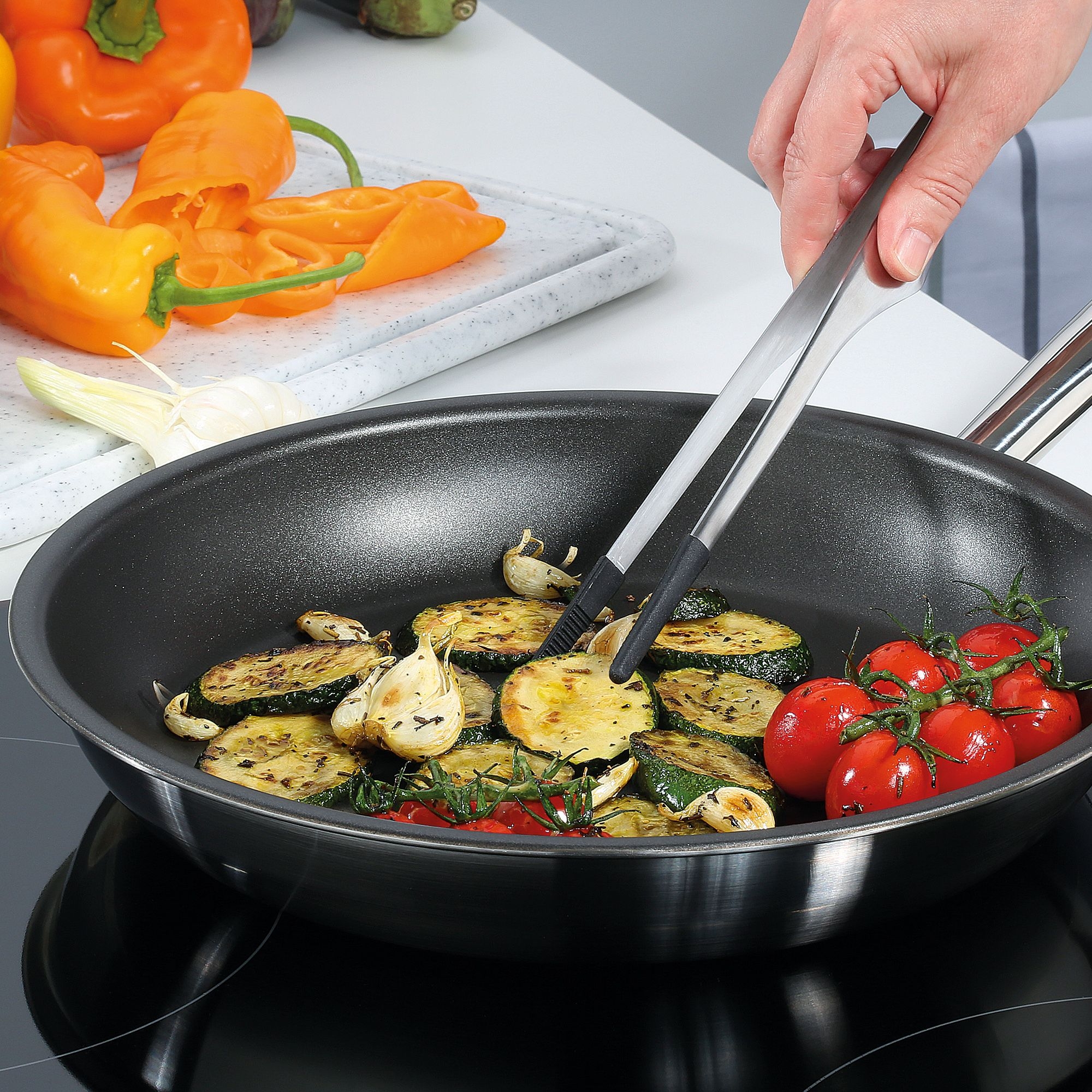 Pan with fried vegetables and tomatoes on stove