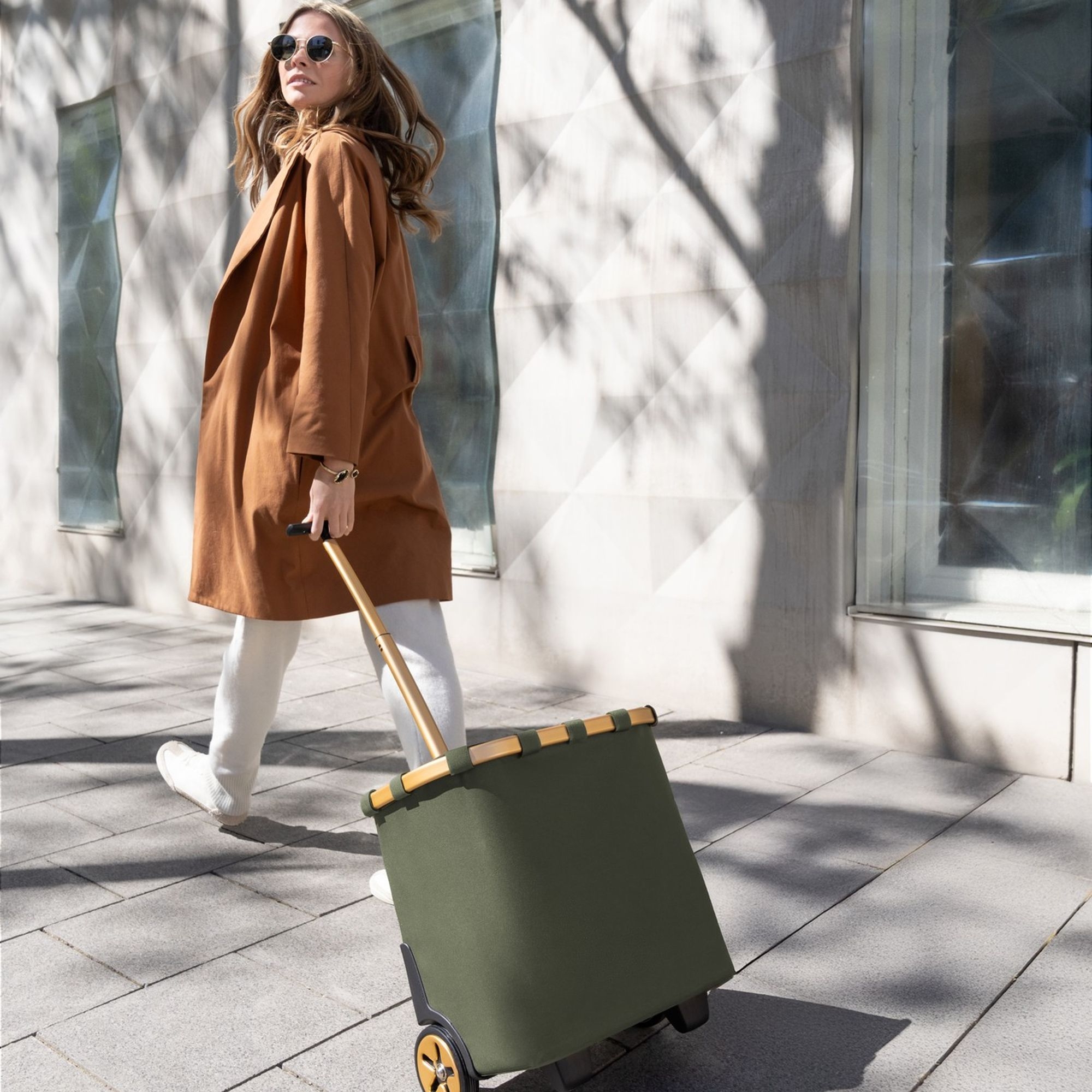 Woman pulling green shopping trolley with wooden handle