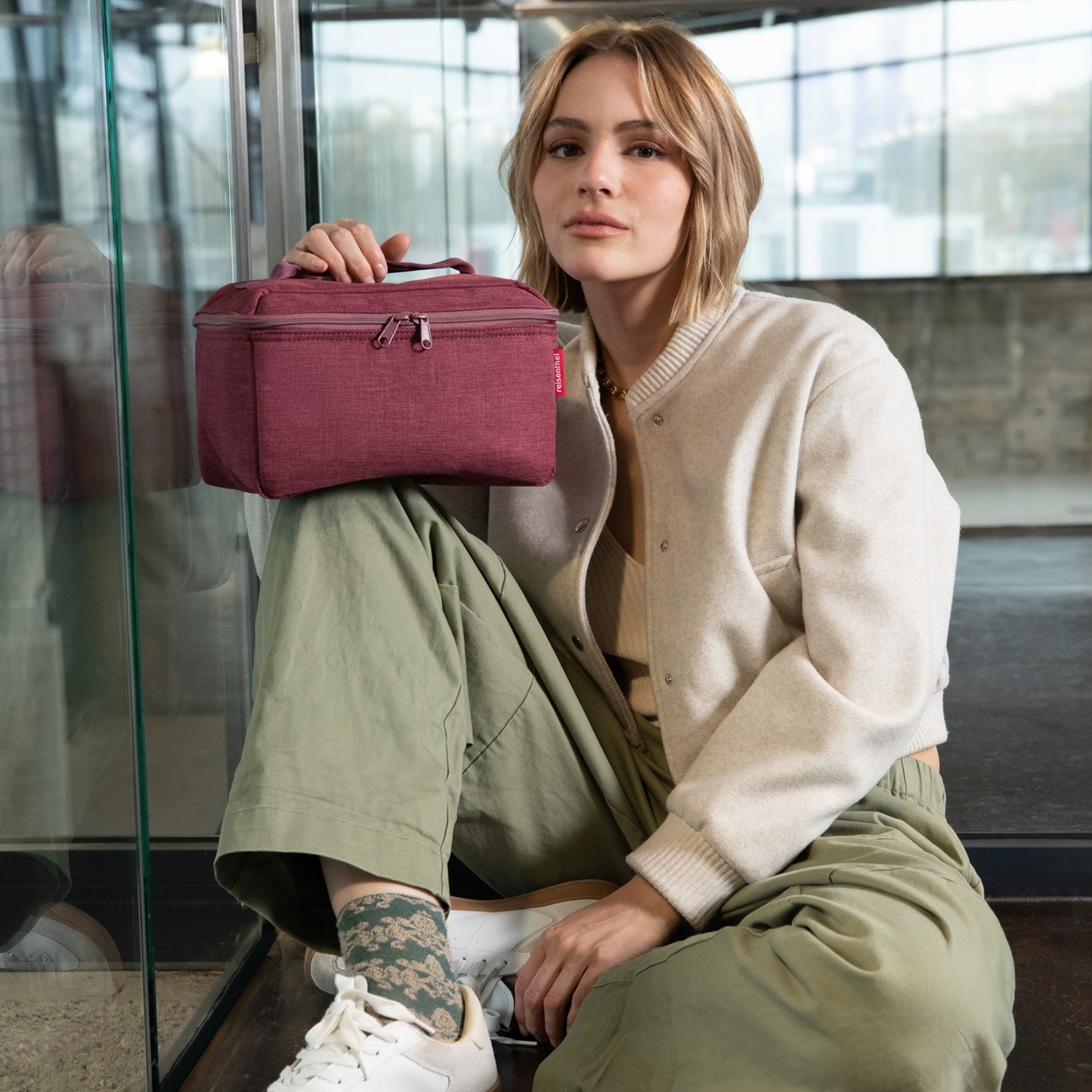 Woman sitting with red cosmetic bag and casual outfit