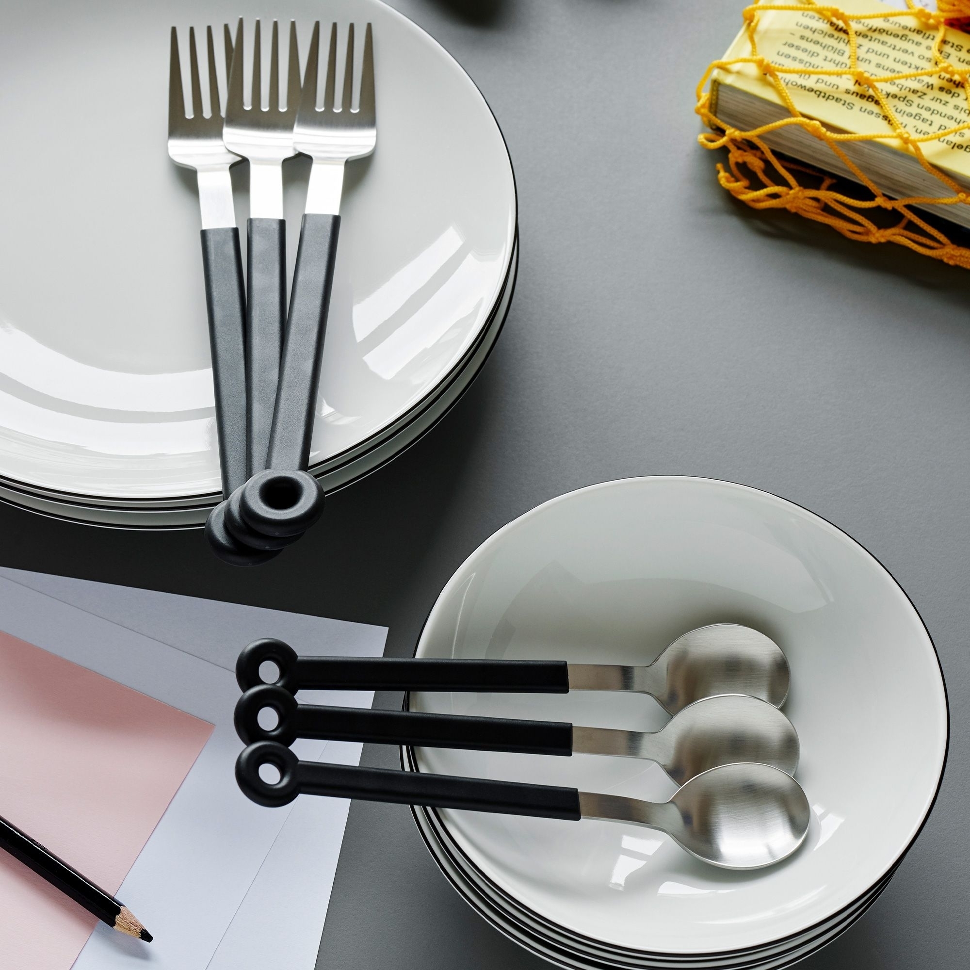 Modernes Besteck auf weißen Tellern und Schalen