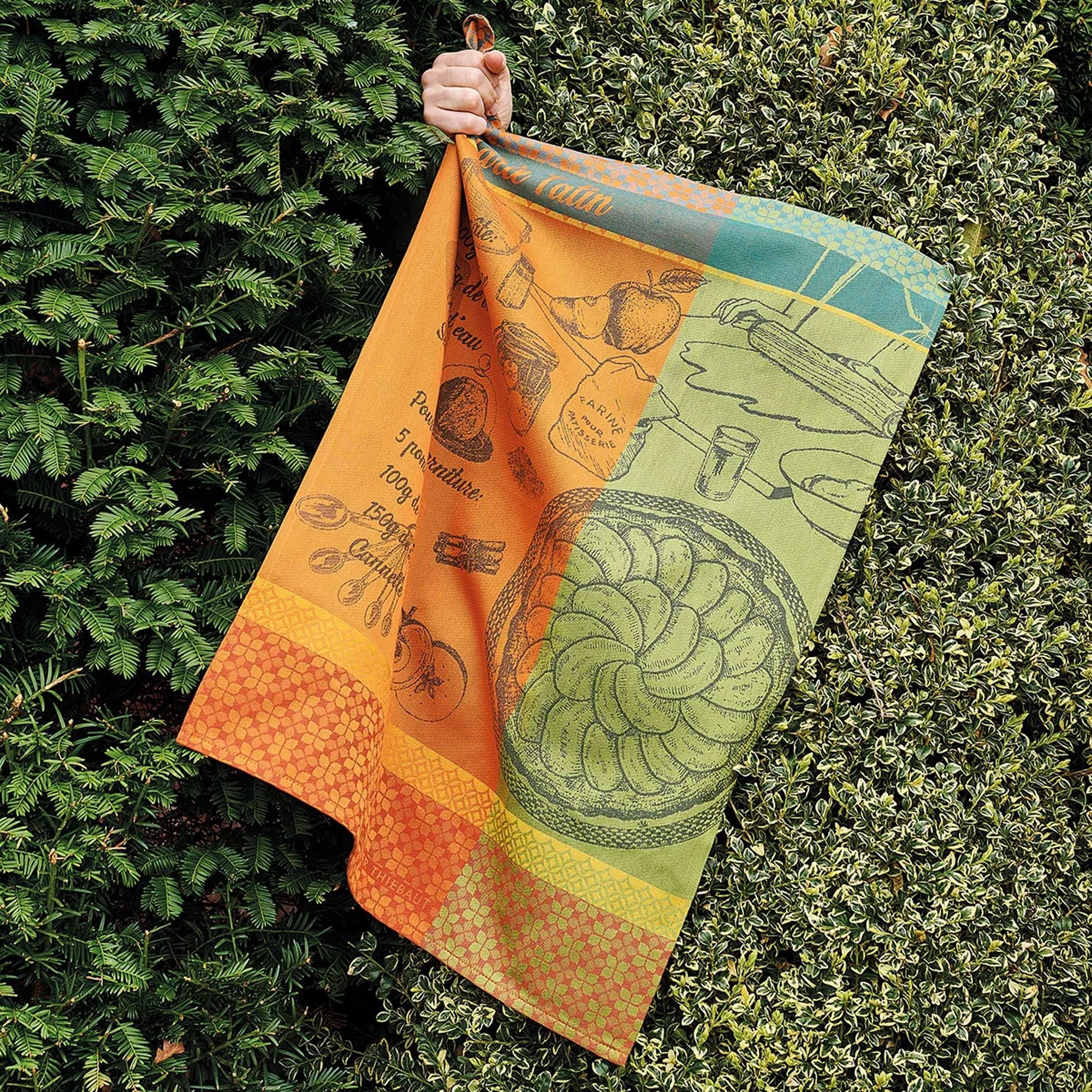 Hand hält buntes Küchentuch mit Obst- und Rezeptdruck