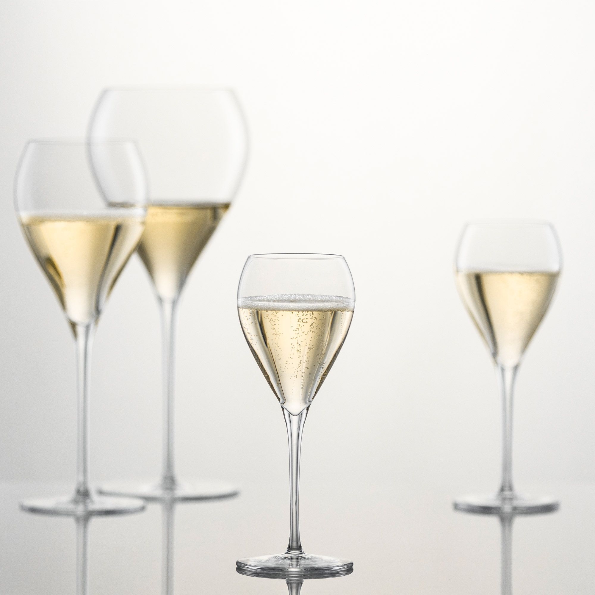 Four filled champagne glasses on glass surface