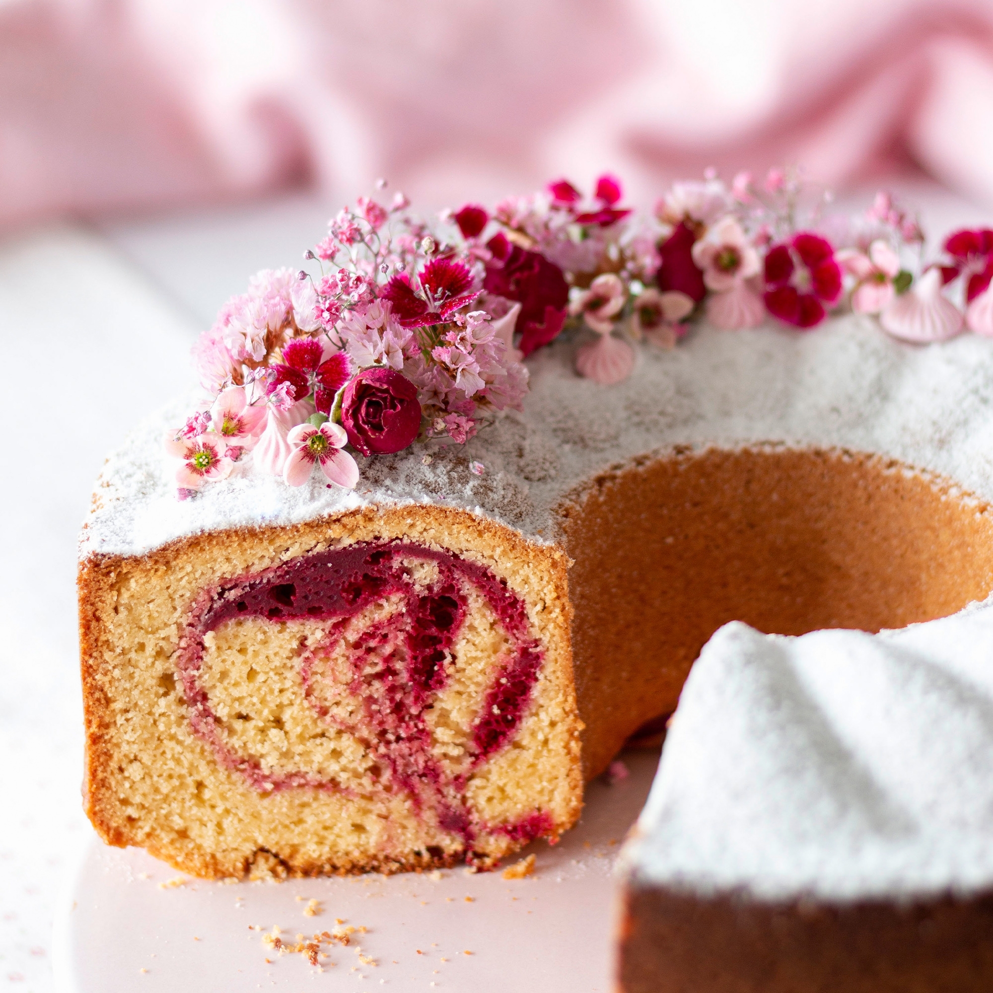 Anschnitt eines Beeren-Gugelhupfs mit Blütendeko