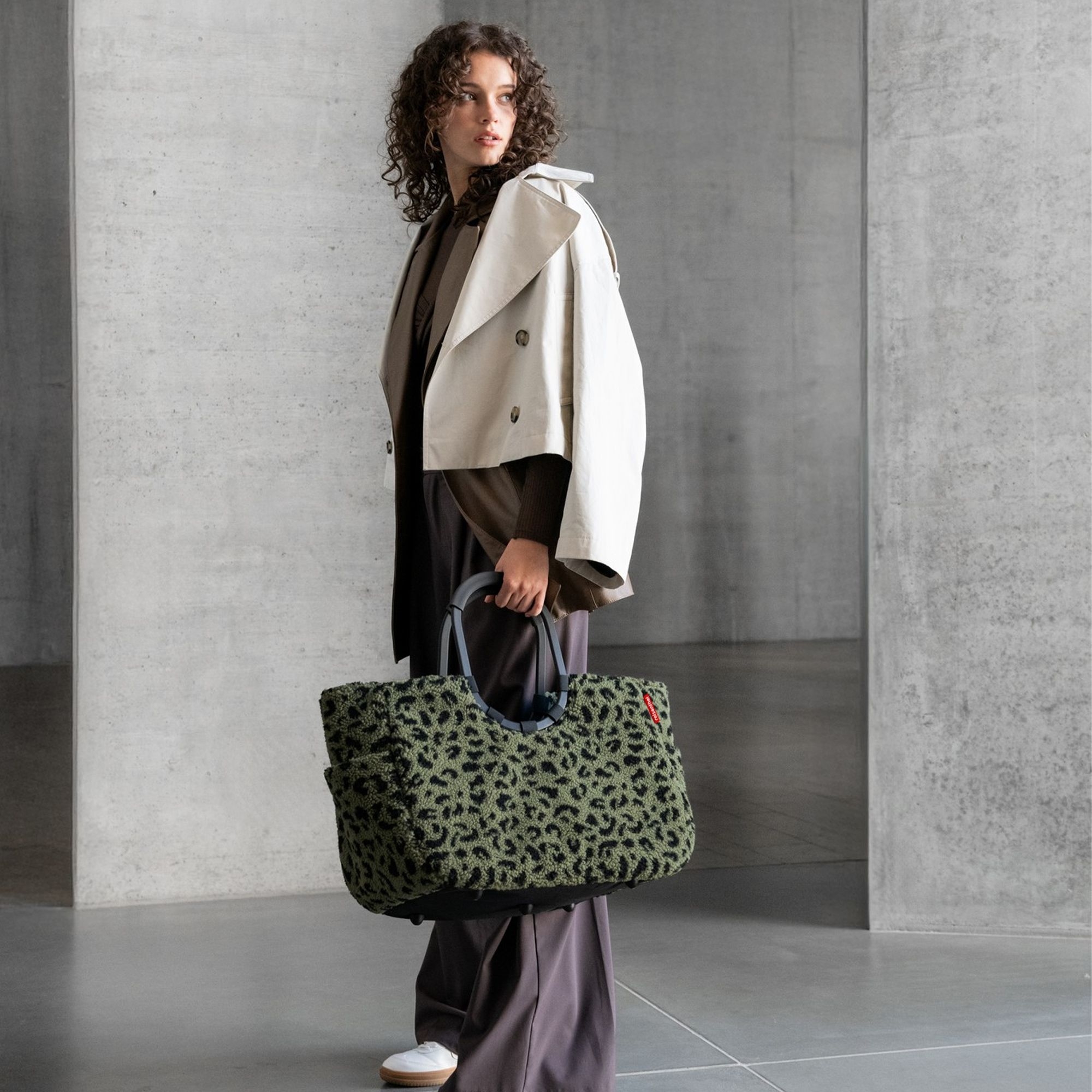 Woman carrying large green leopard print bag with grey handl