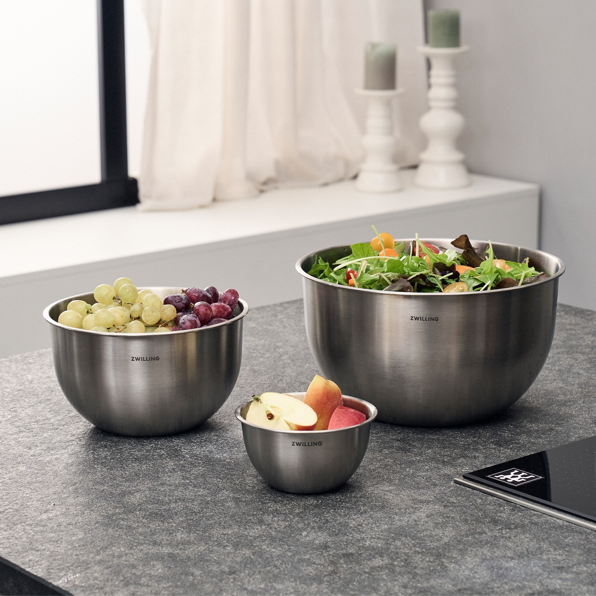 Three stainless steel bowls with fruit and salad on kitchen
