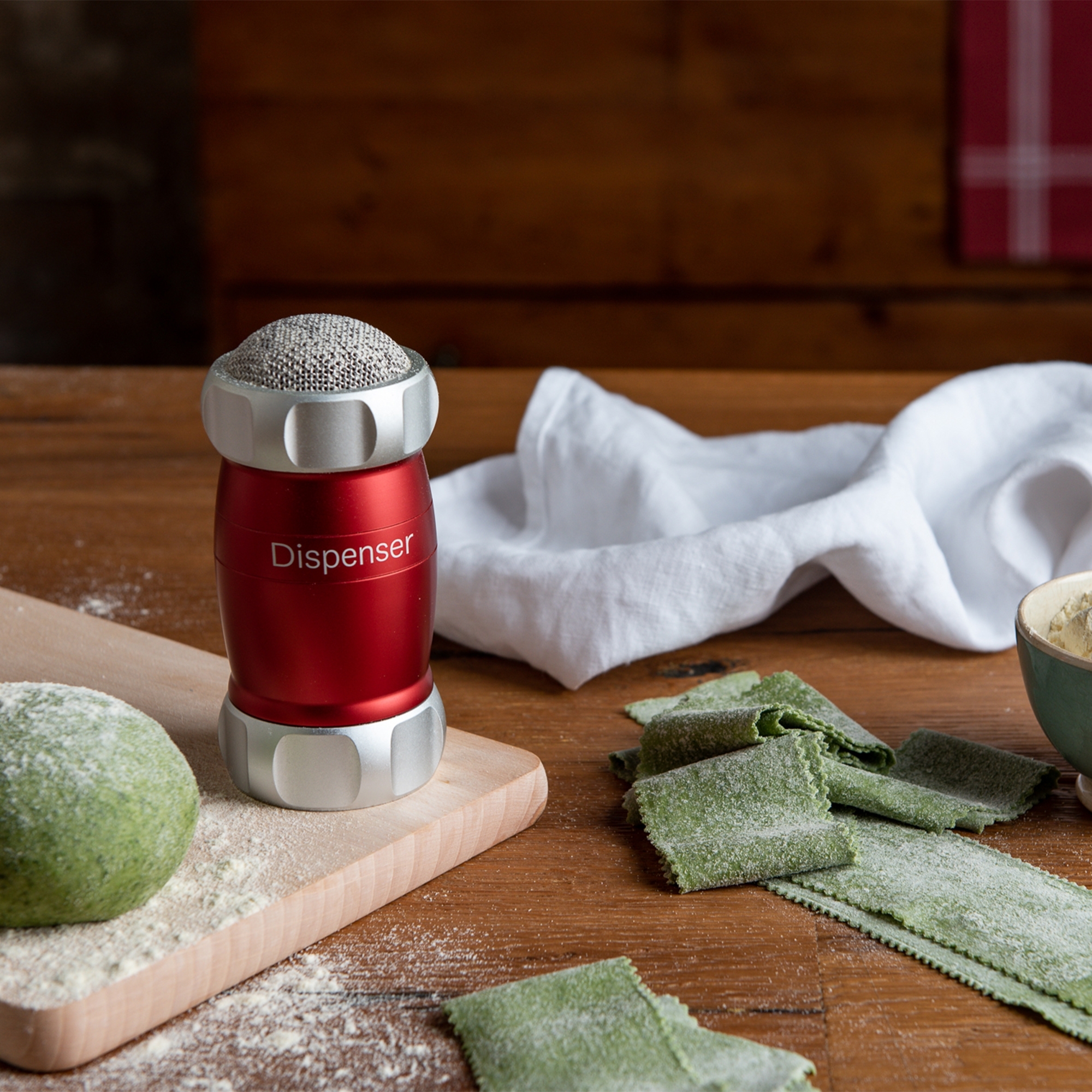 Roter Mehlstreuer auf Holzbrett mit frischer Pasta