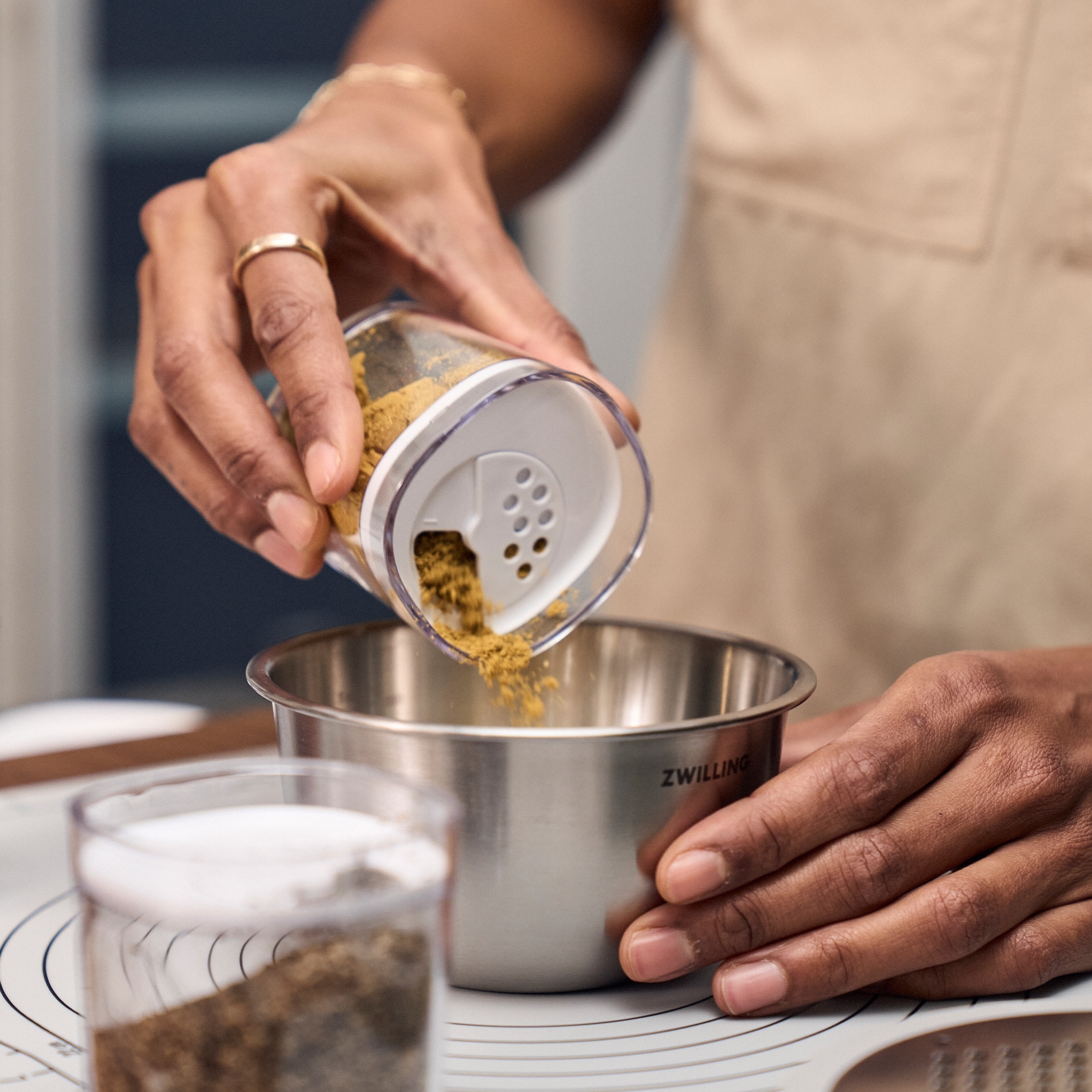 Person pouring spice into stainless steel bowl