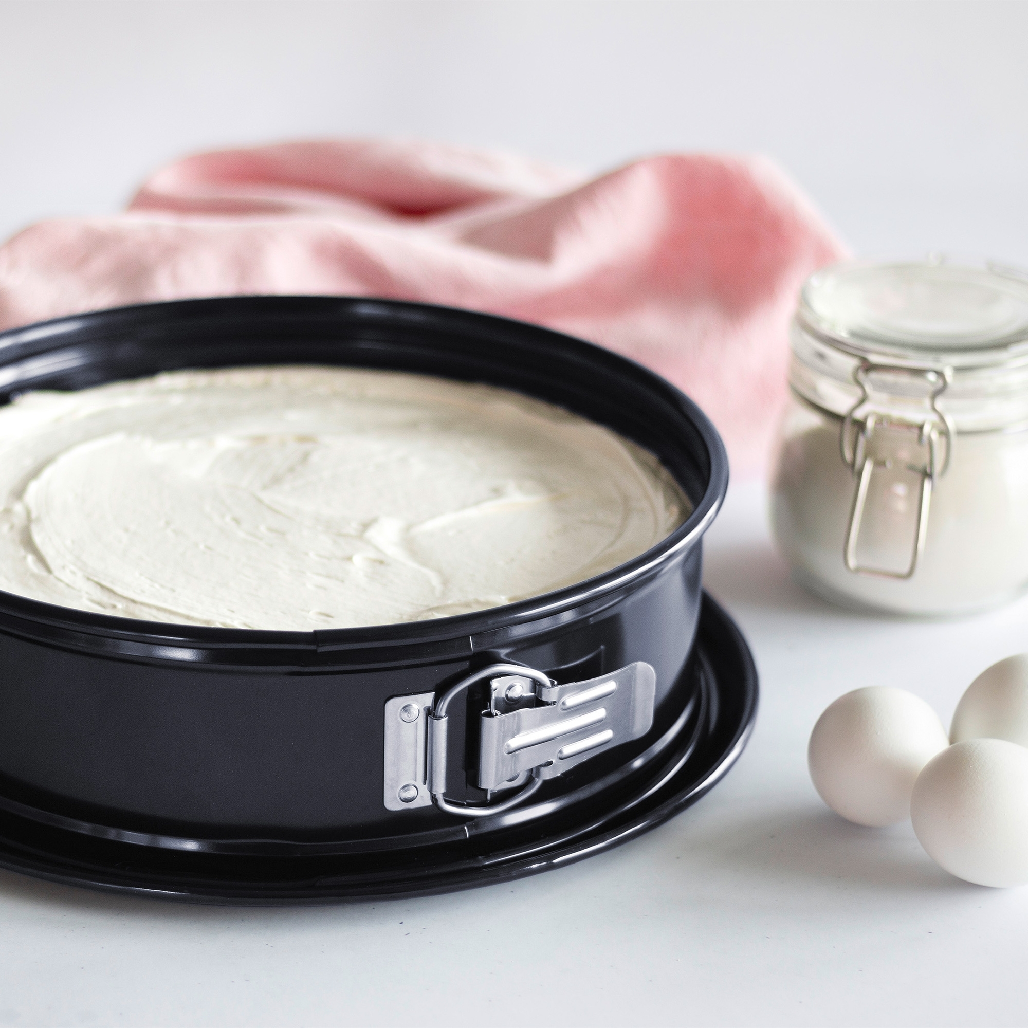 Schwarze Springform mit hellem Kuchenteig gefüllt