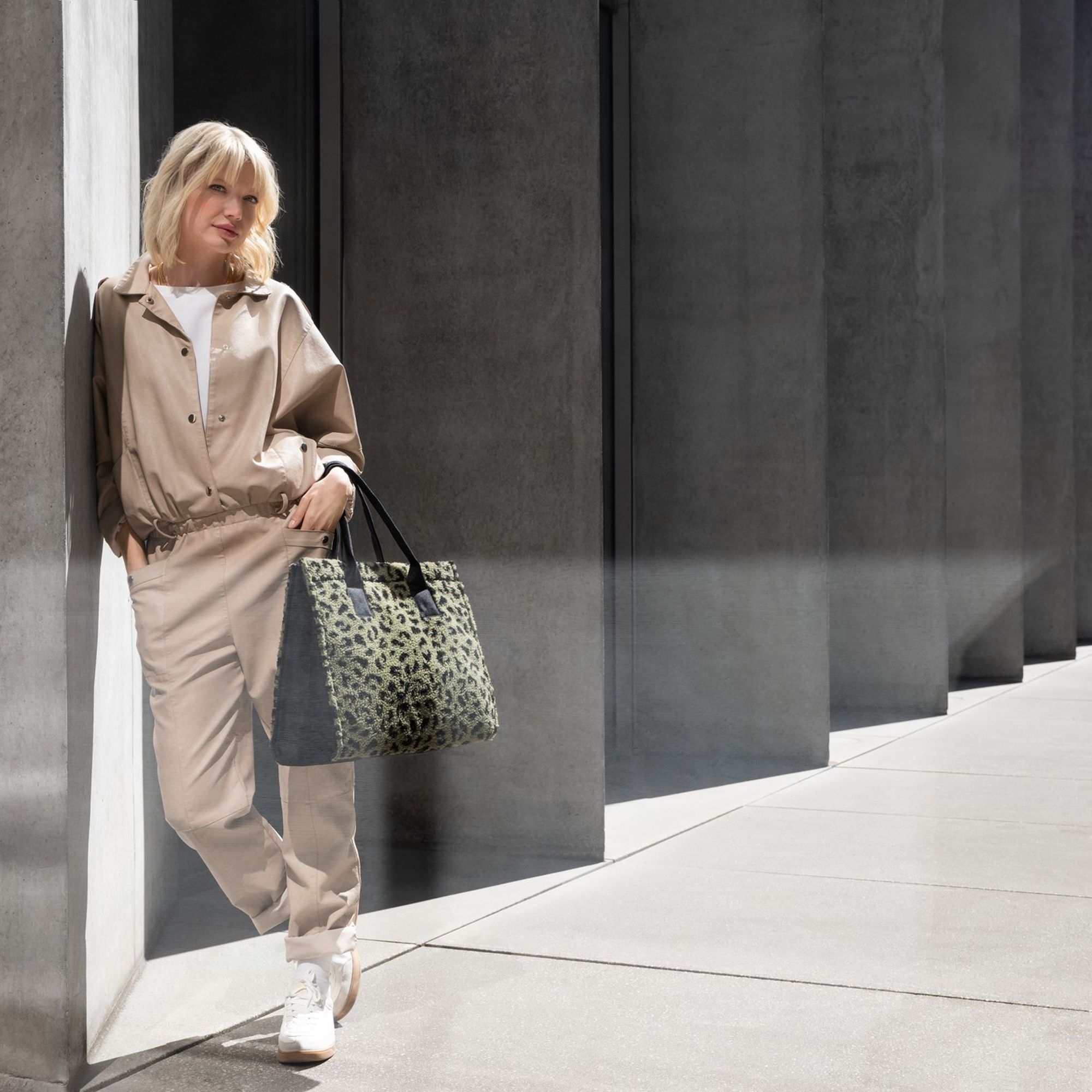 Woman wearing beige outfit holding large leopard print bag