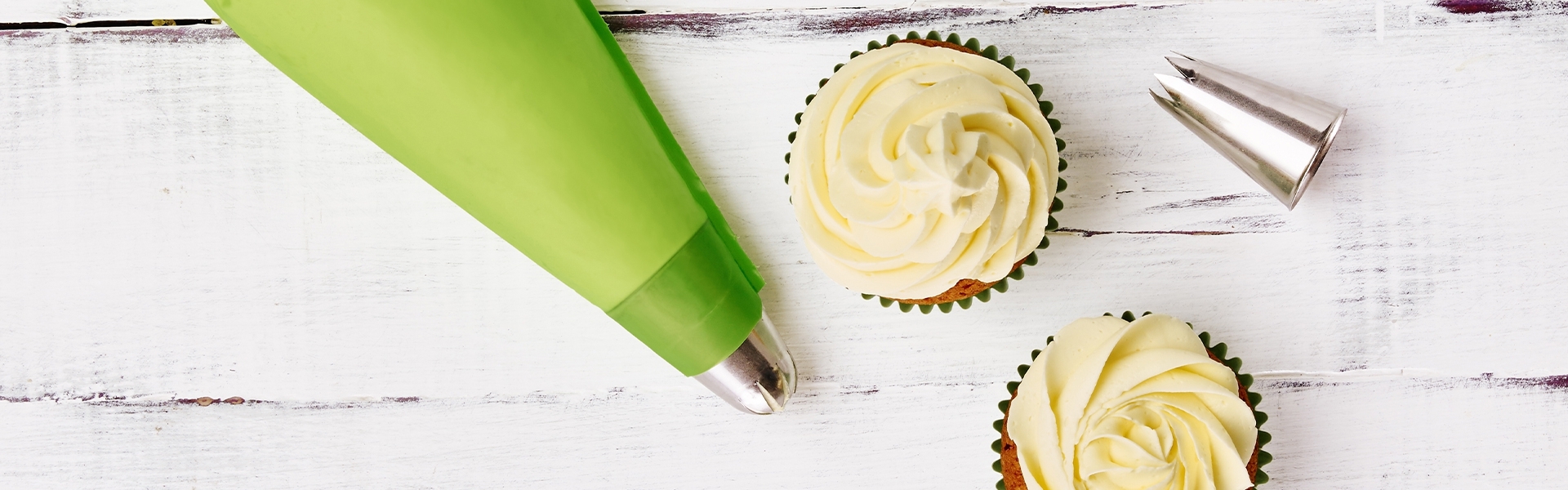 Green piping bag, nozzles and cupcakes