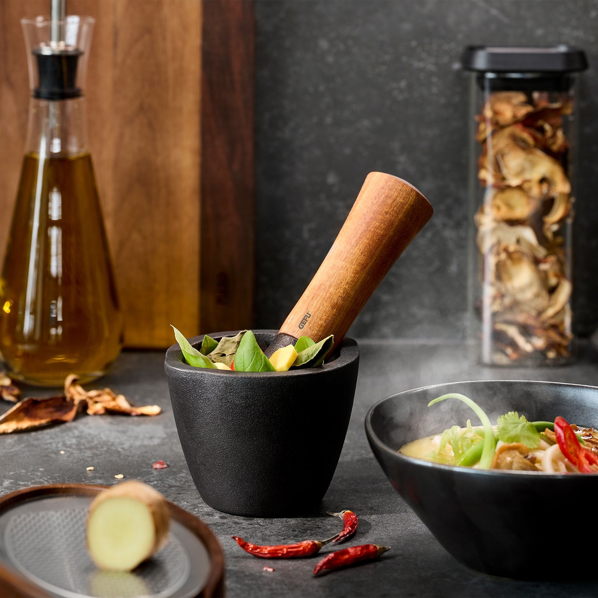 Black mortar with wooden pestle and fresh herbs