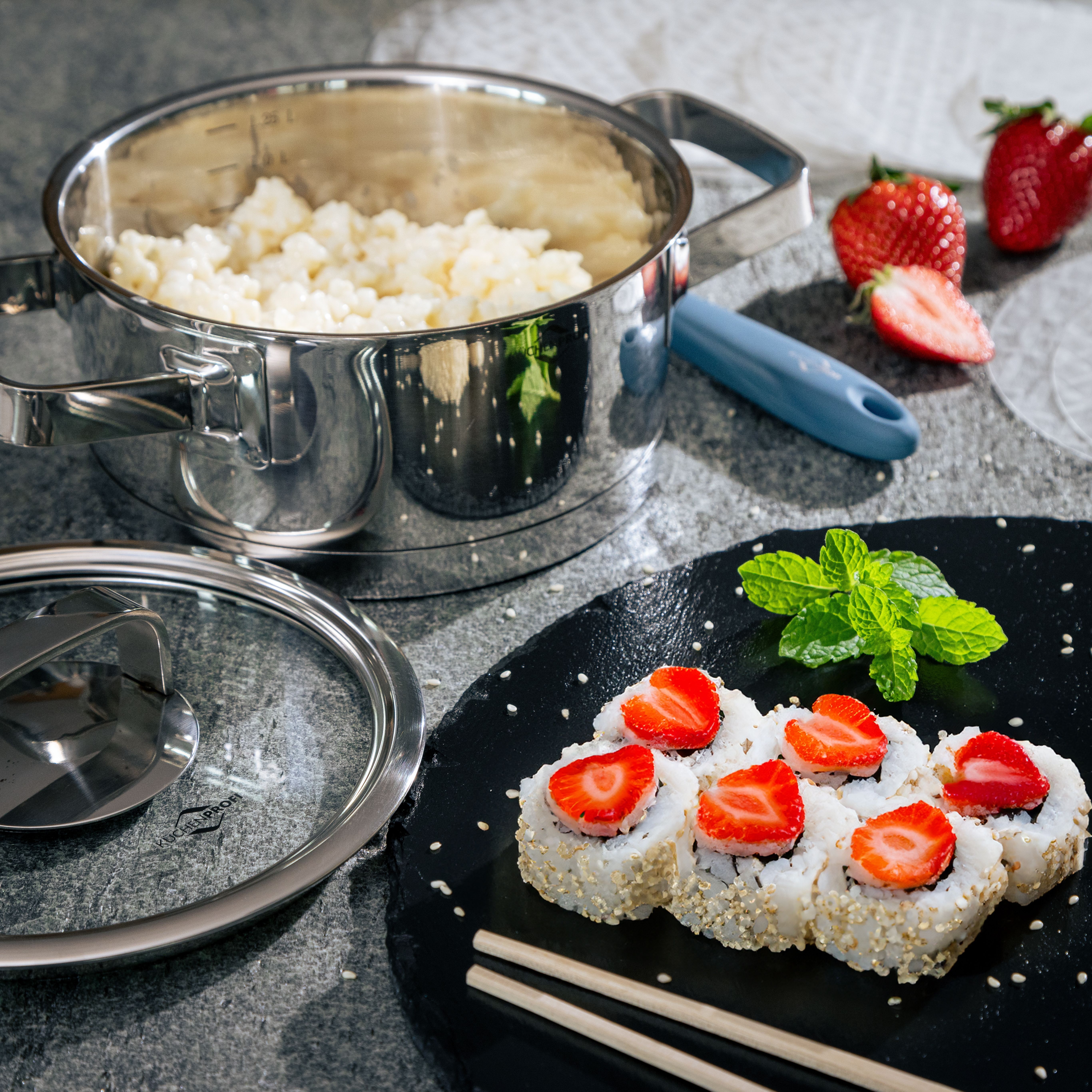Slate plate with strawberry sushi, pot in background