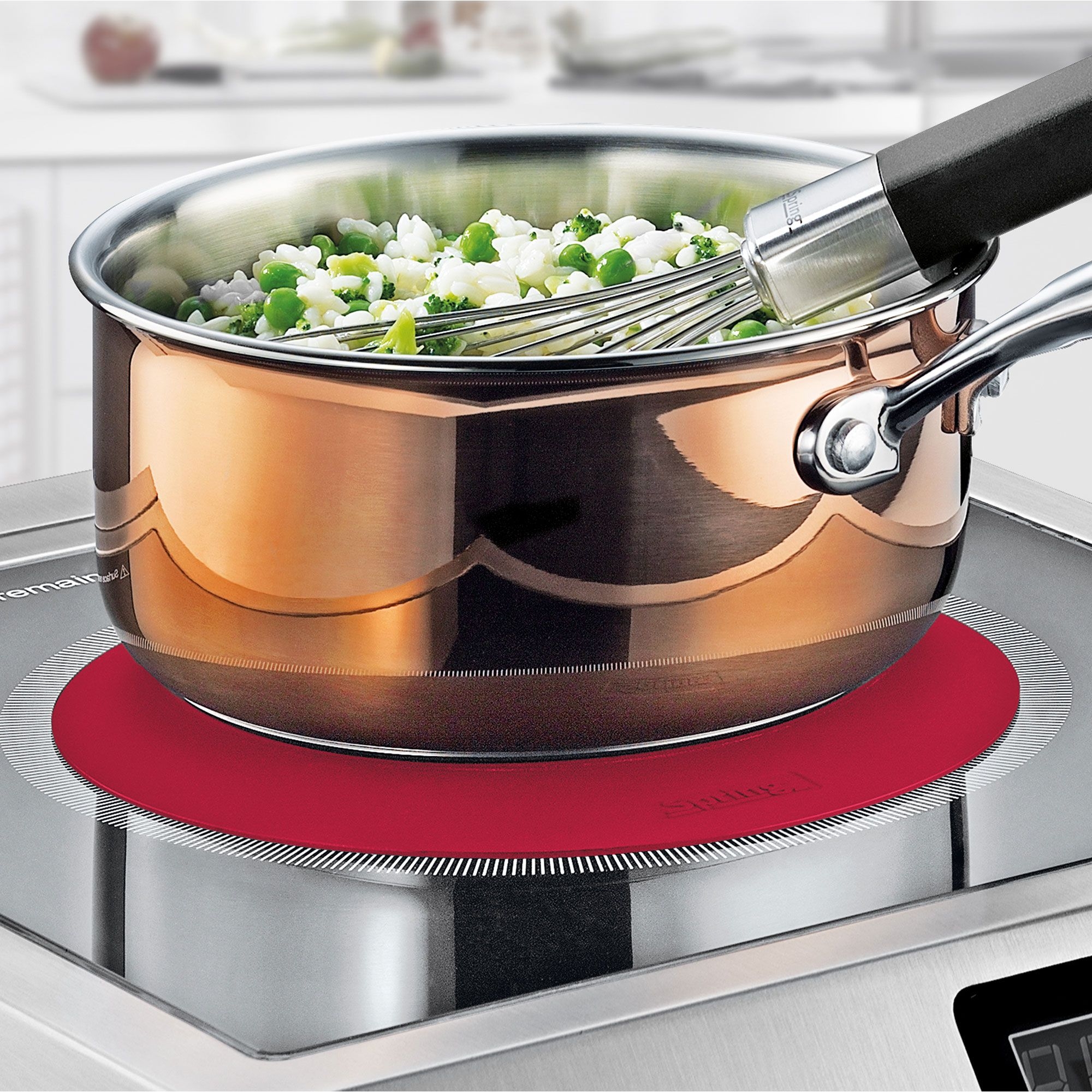 Copper pot with vegetables and whisk on hob