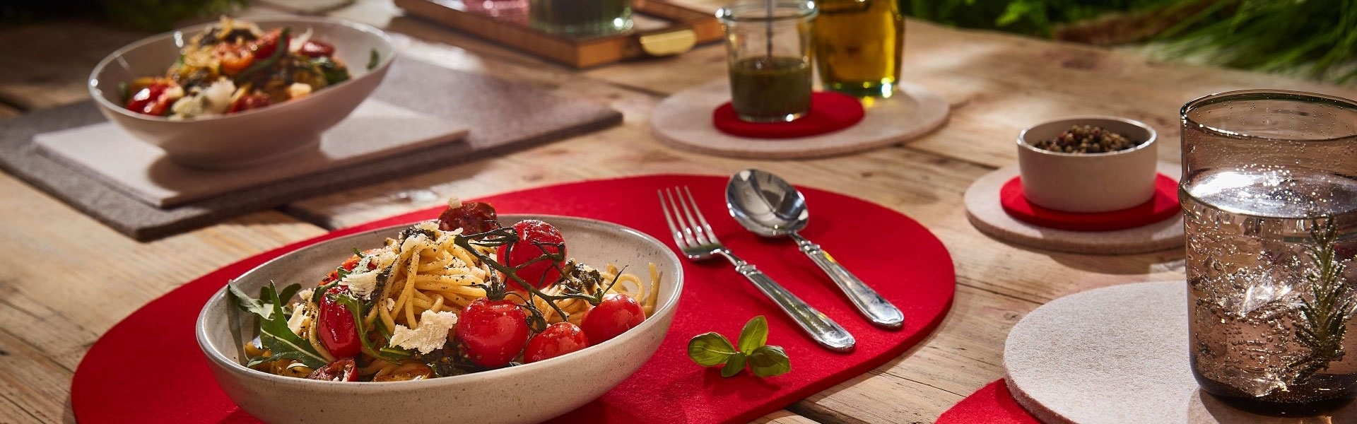 Dining table with red placemats and pasta bowls