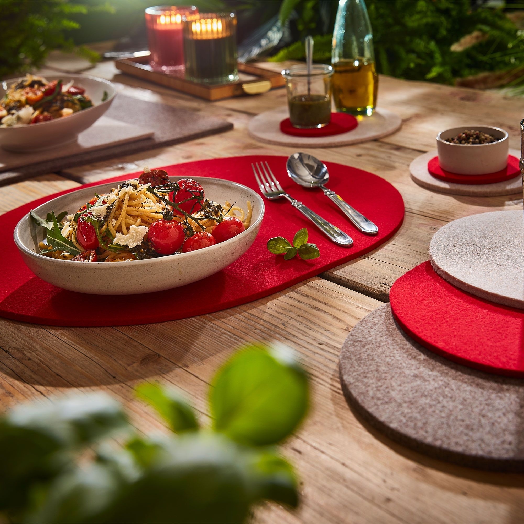 Gedeckter Tisch mit roten Filz-Tischsets und Pasta