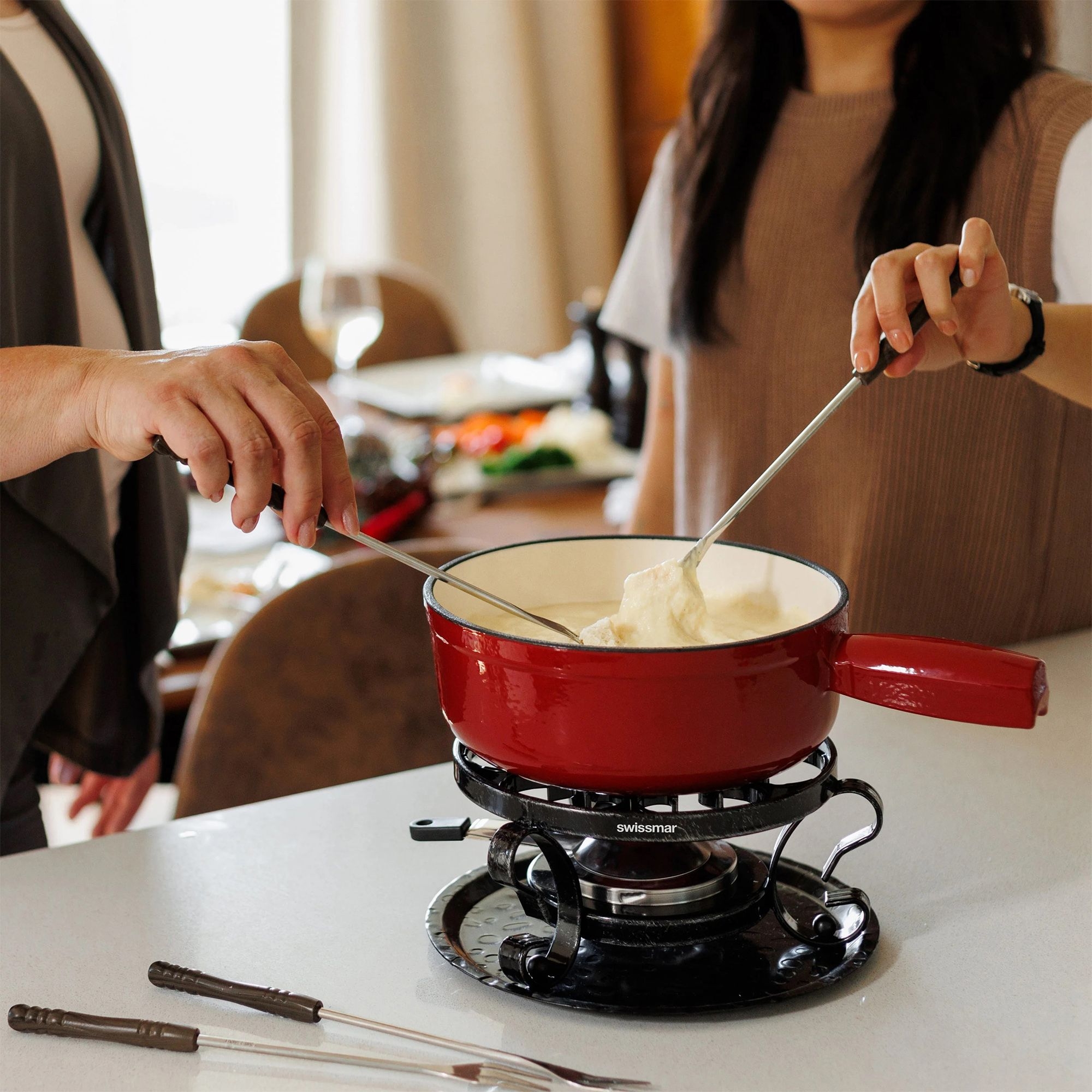 People enjoying cheese fondue in red pot