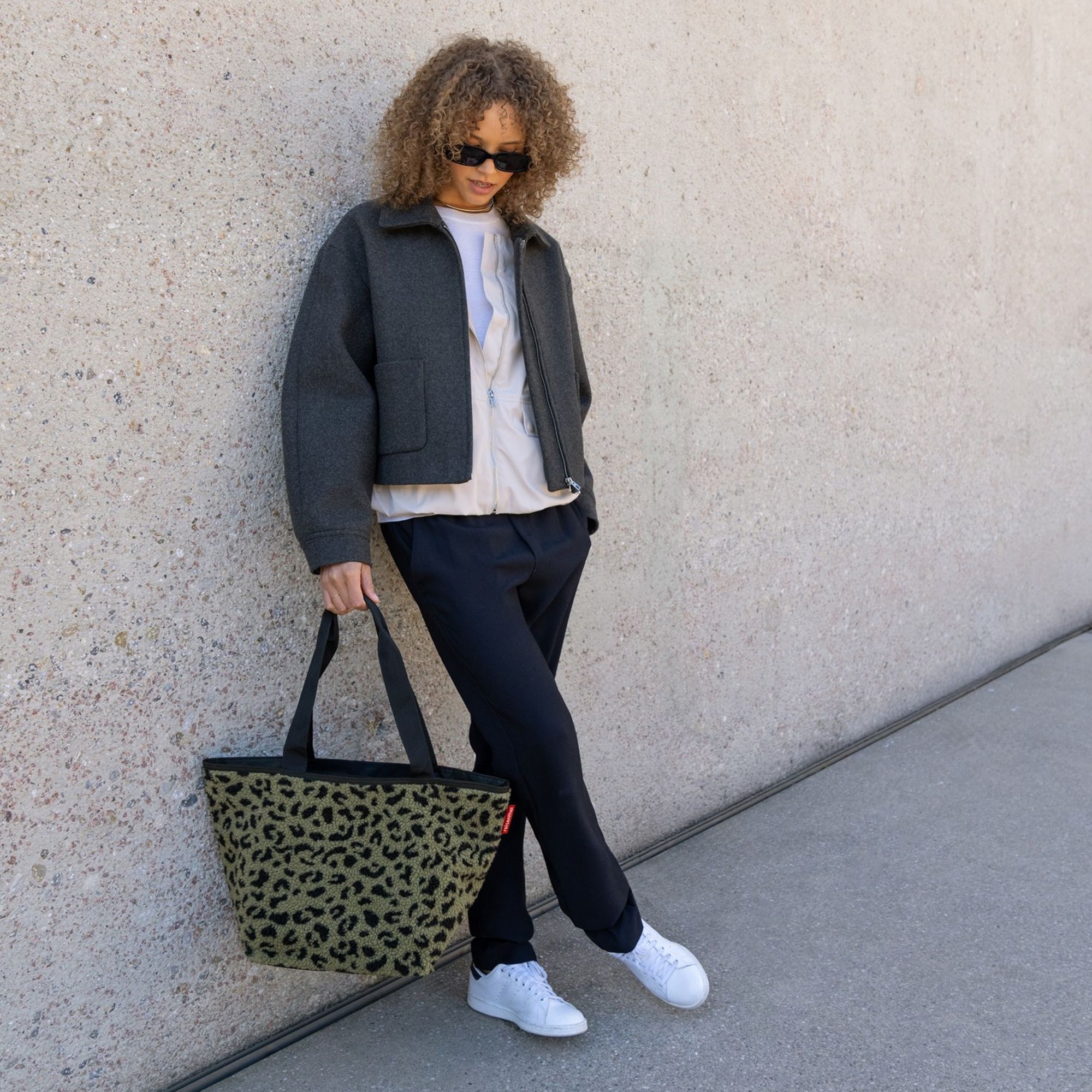 Fashionable woman holding green leopard print bag by street
