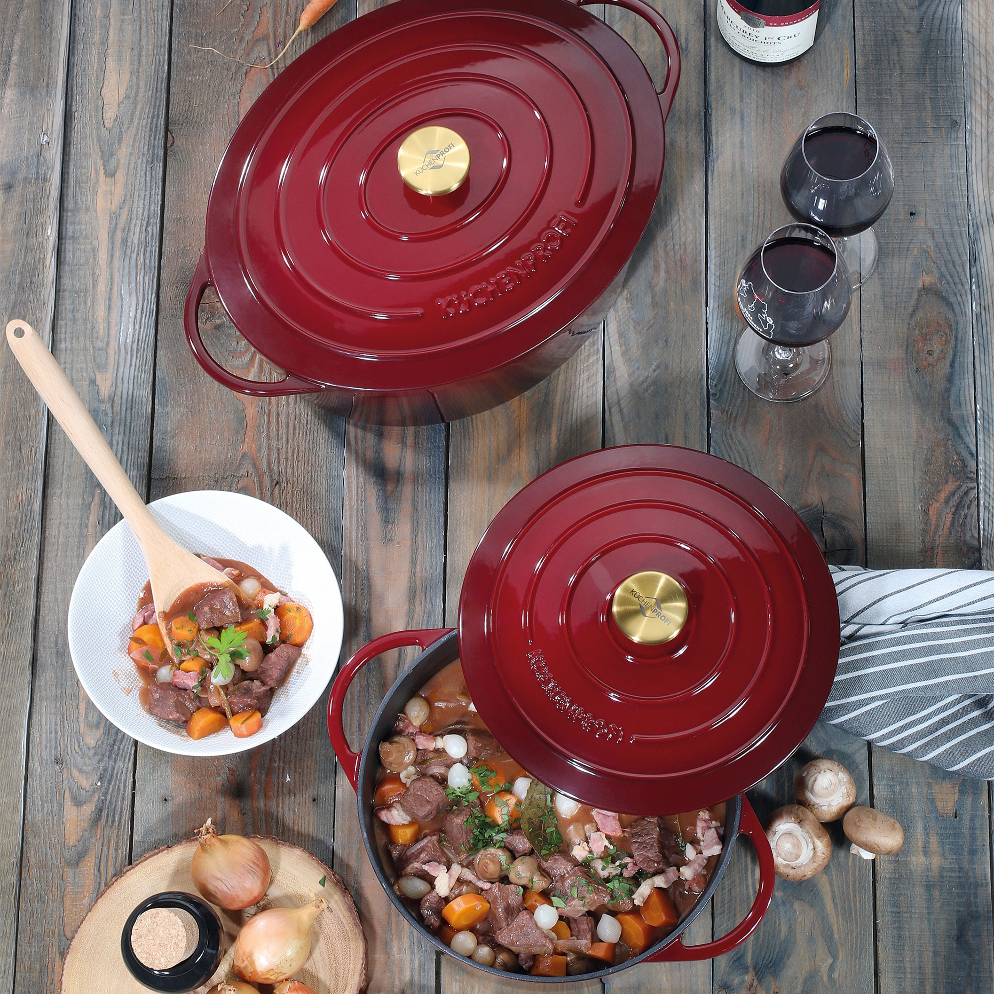 Red cast iron casserole with stew on wooden table