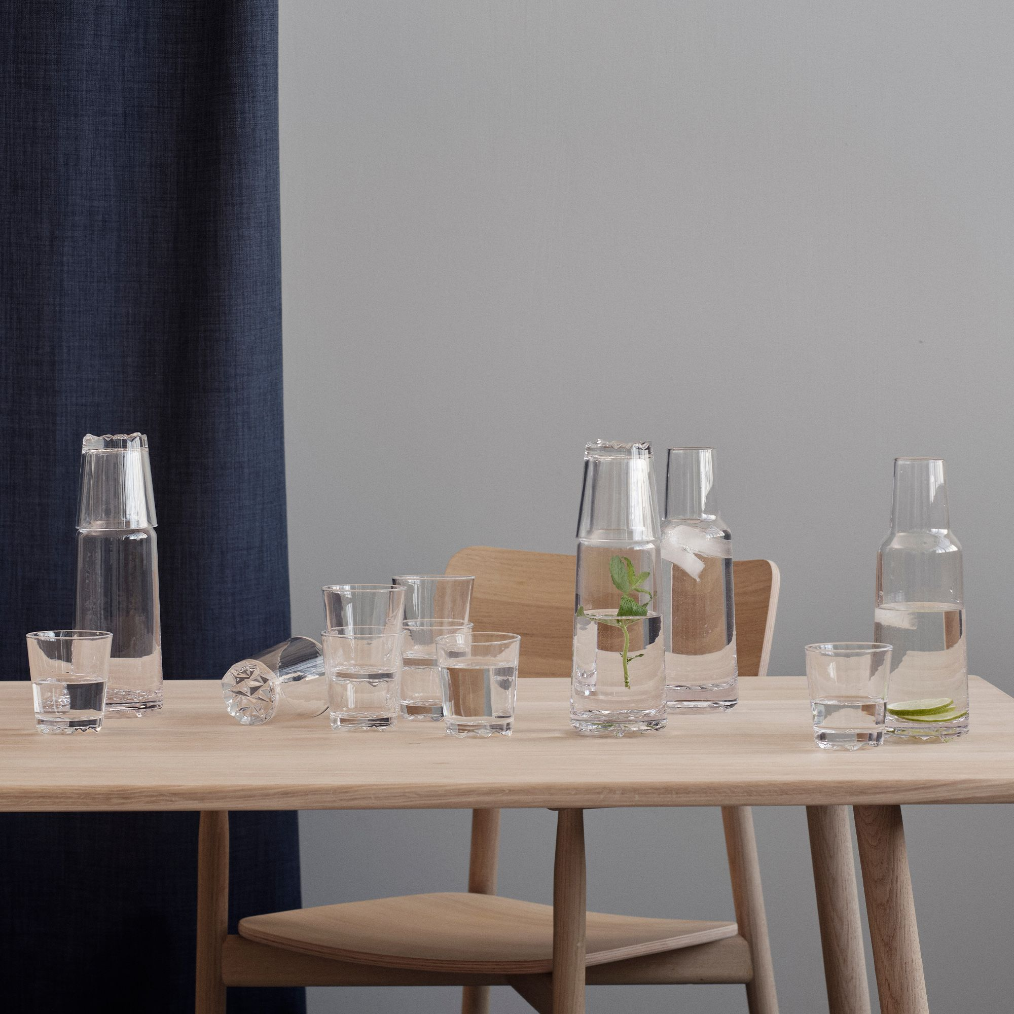 Several glass water carafes and tumblers on wood table