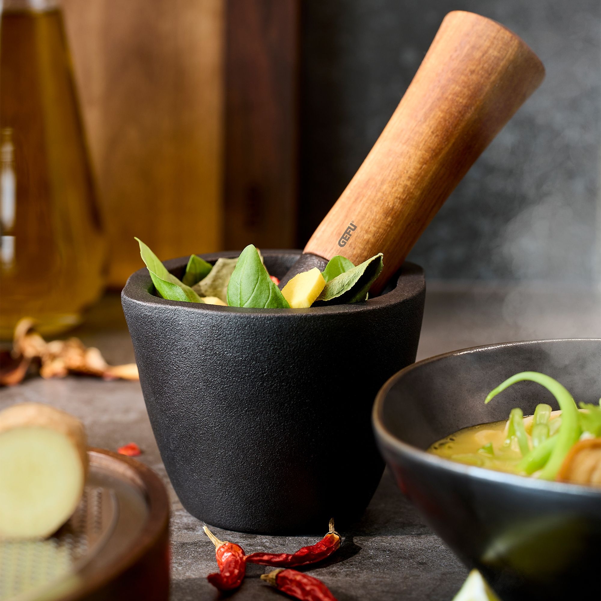 Black mortar with wooden pestle and fresh herbs