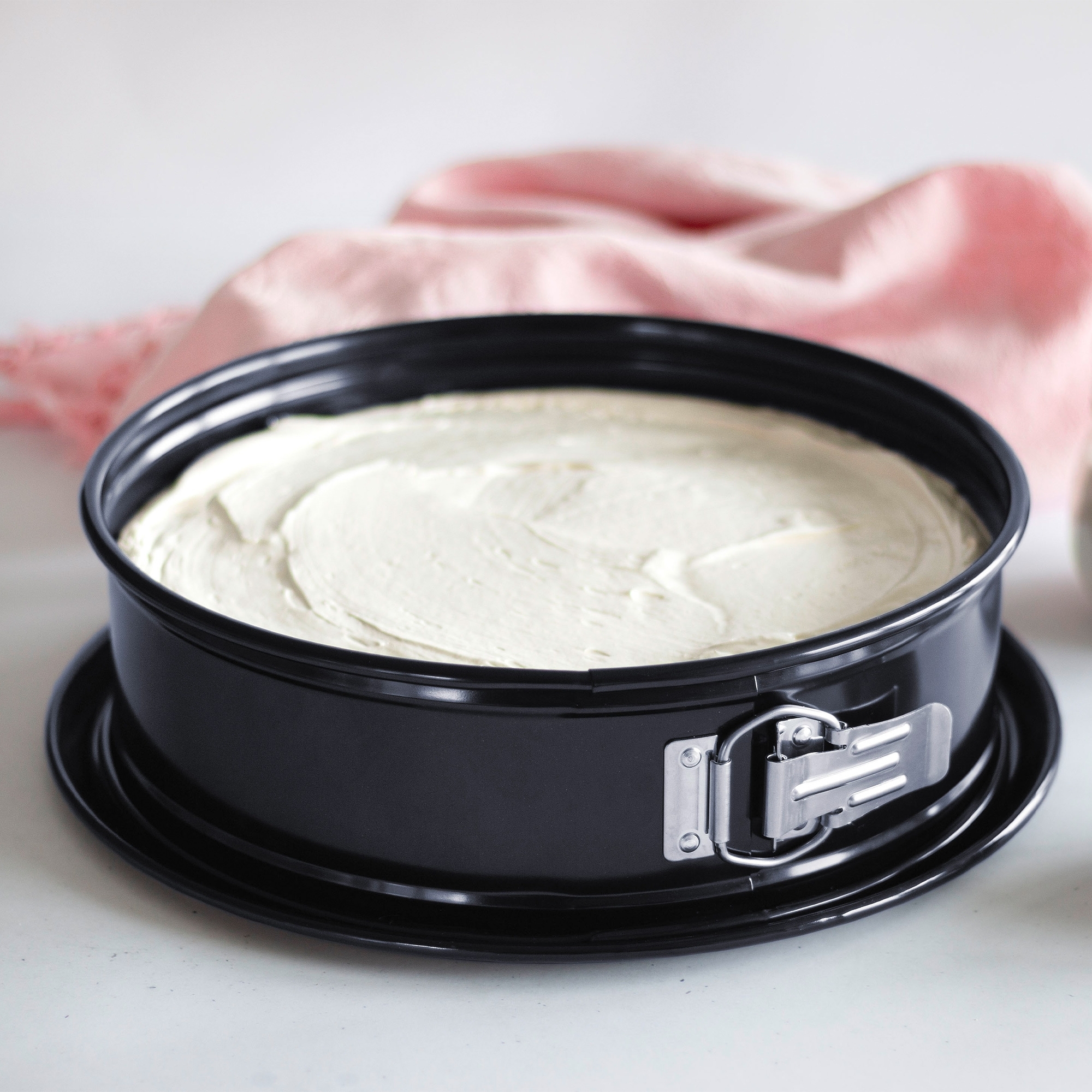 Schwarze Springform mit hellem Kuchenteig befüllt