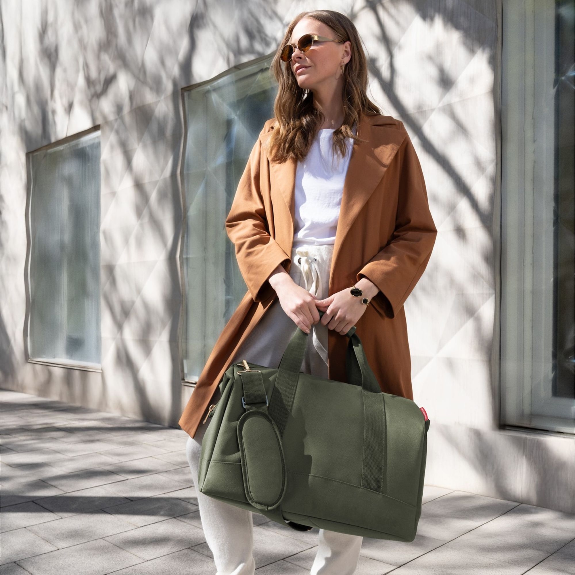 Woman with olive green weekender bag in city style
