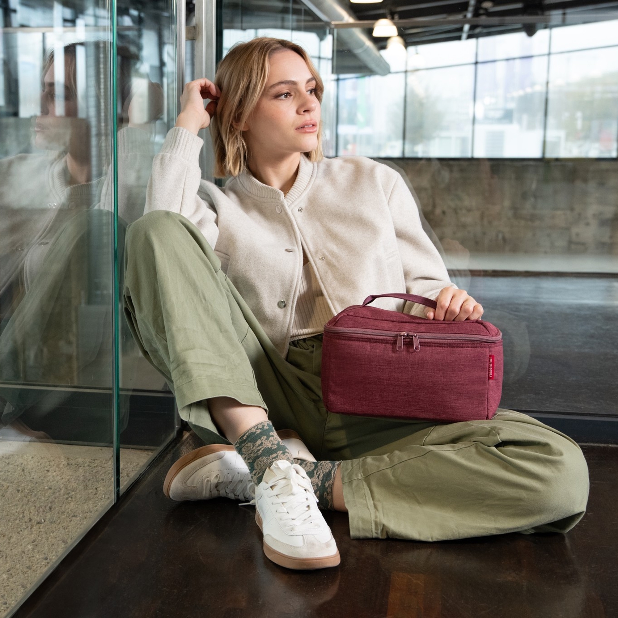 Woman in casual clothes with red bag sitting relaxed on floo