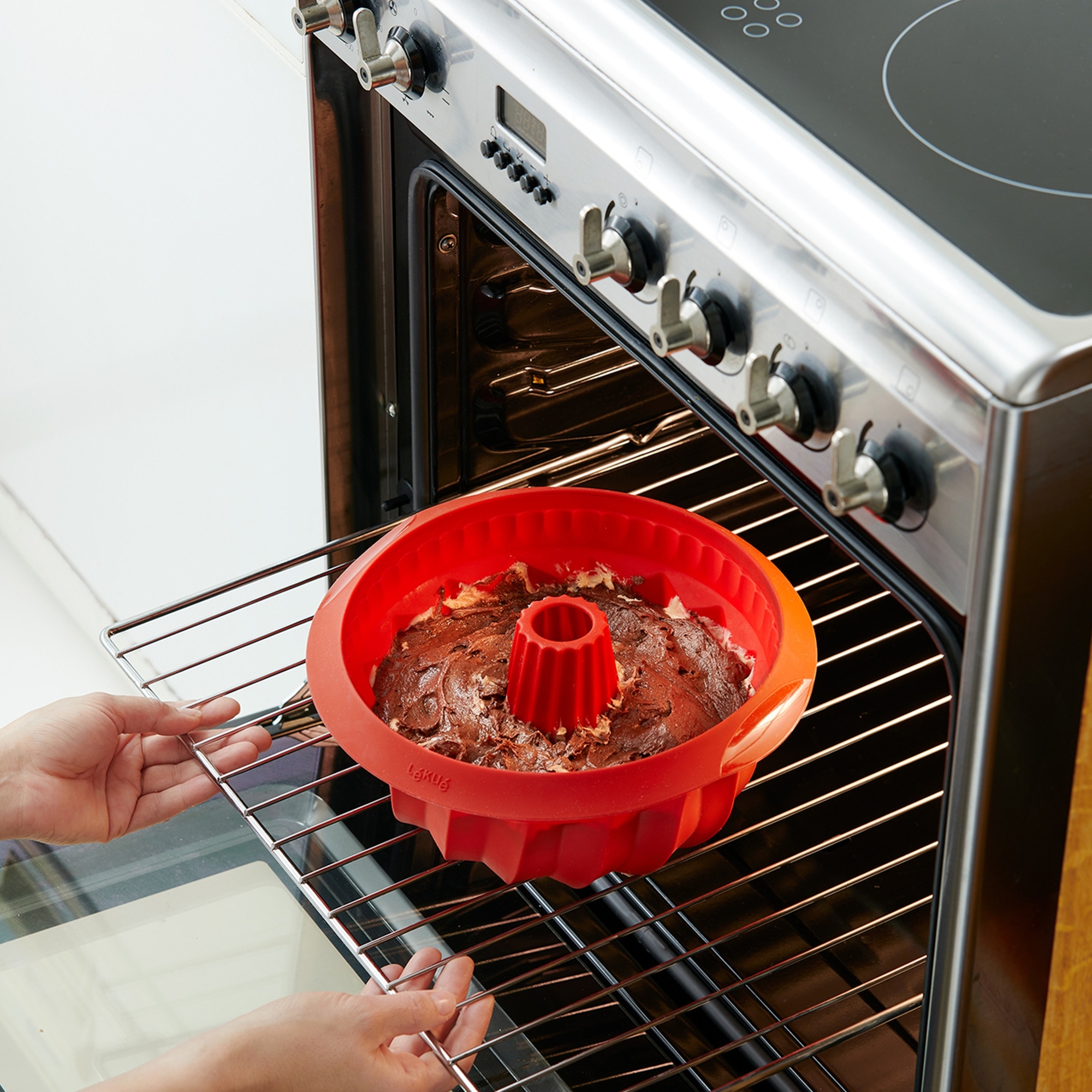 Red silicone bundt cake mould with batter in oven