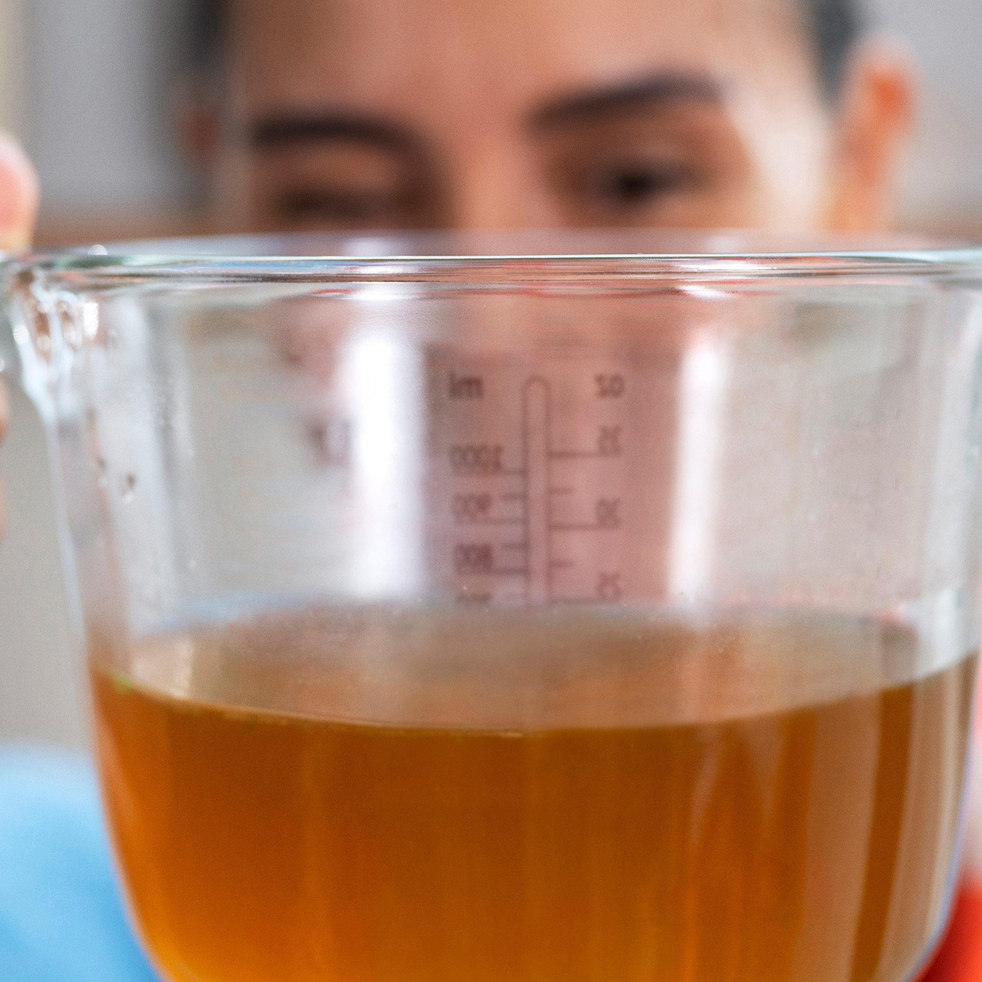 Woman holding measuring jug with clear broth