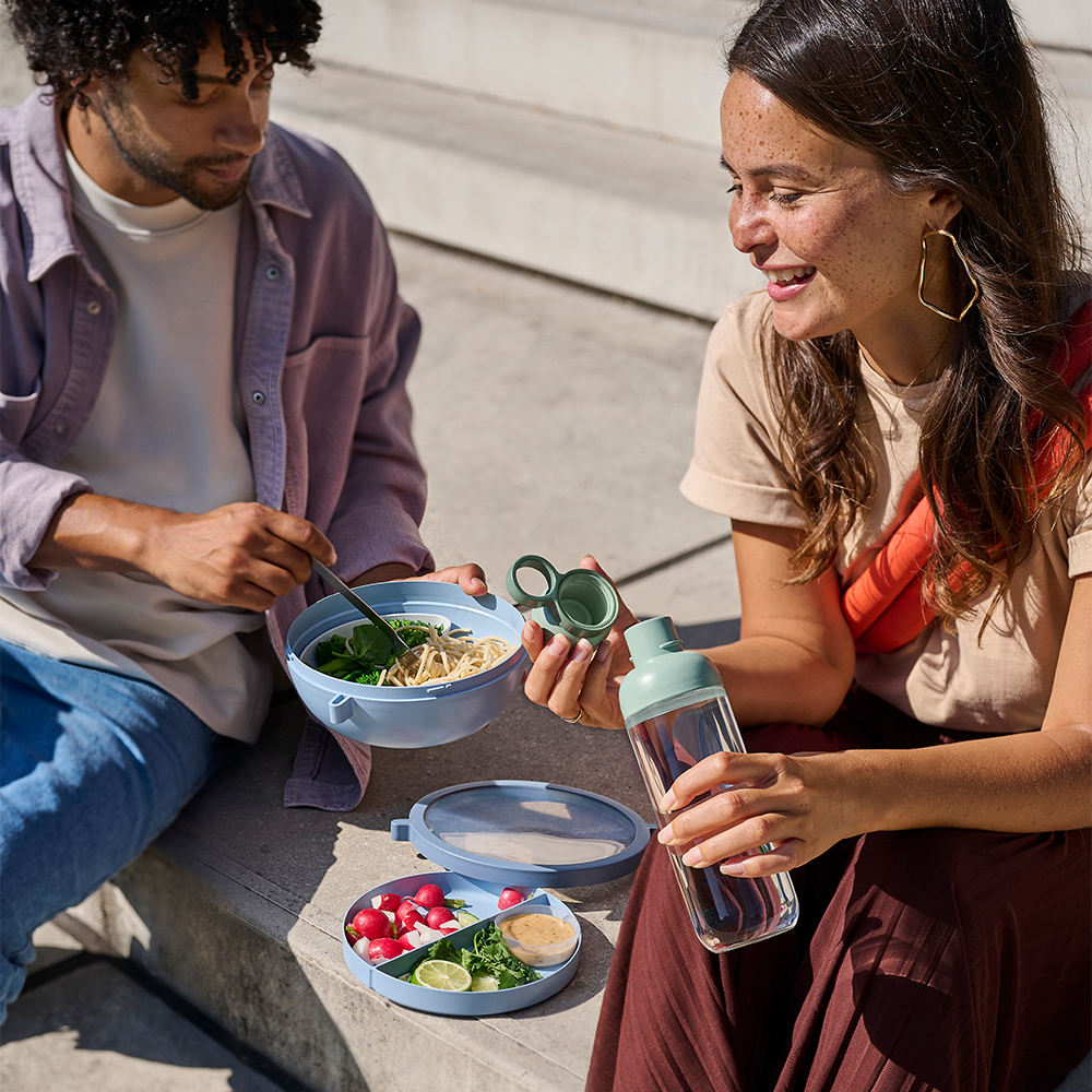 Two people eating with lunch box and bottle