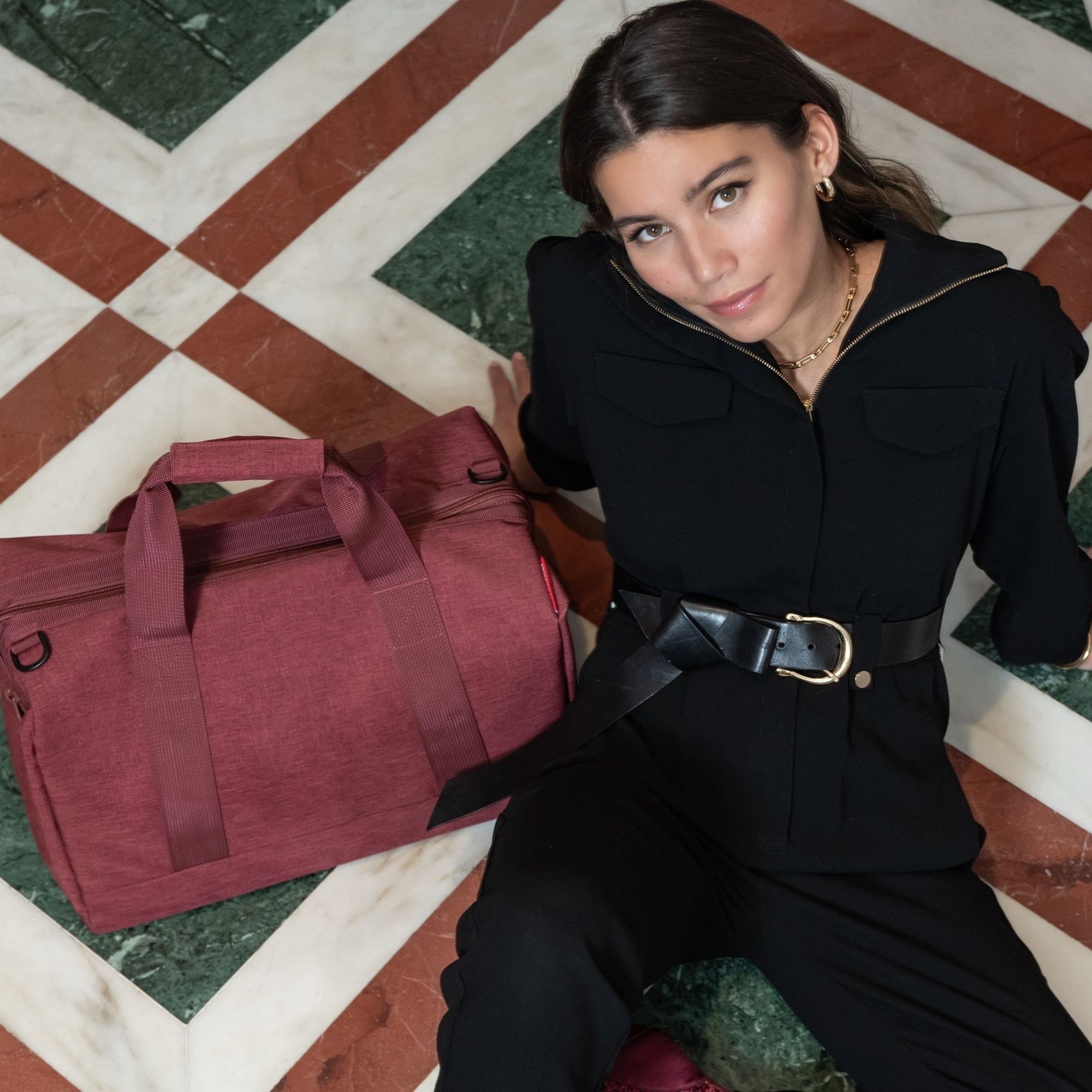 Woman with burgundy weekender bag on tiled floor