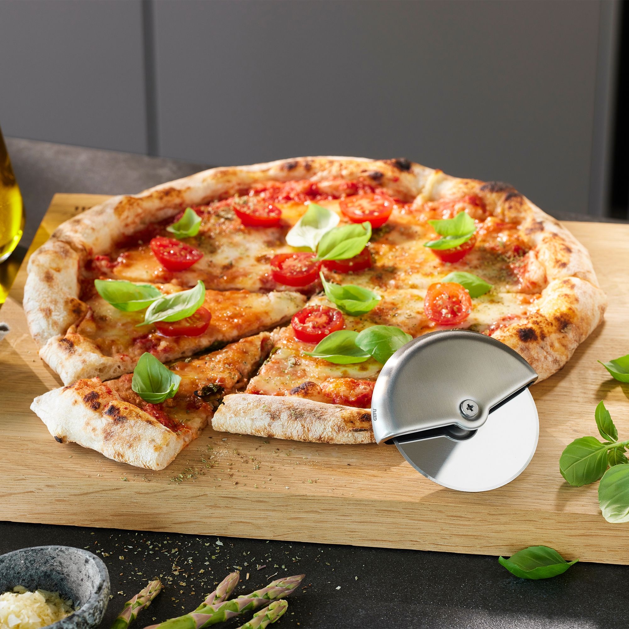 Round pizza cutter beside fresh tomato pizza
