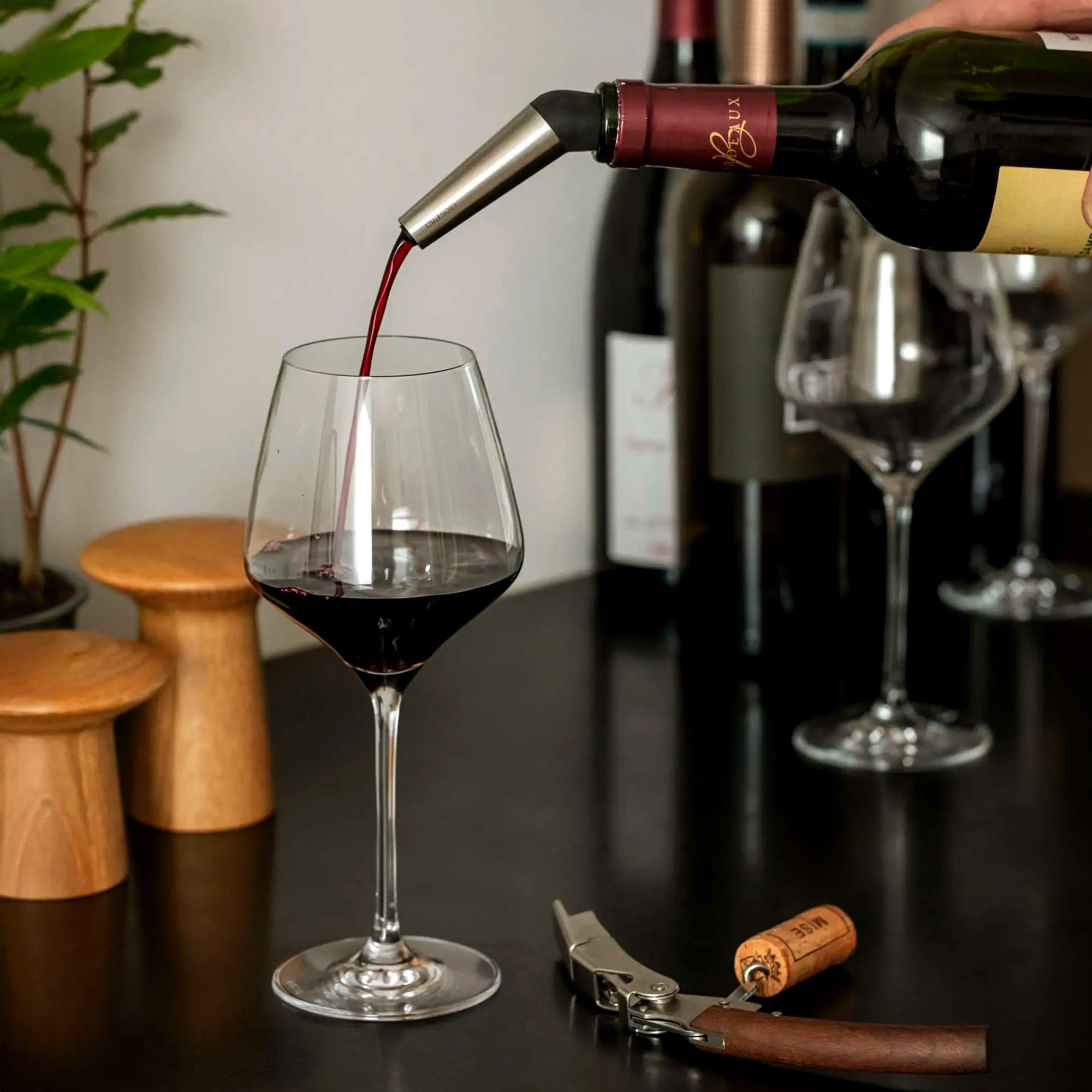 Rotwein wird mit Ausgießer ins Glas eingeschenkt