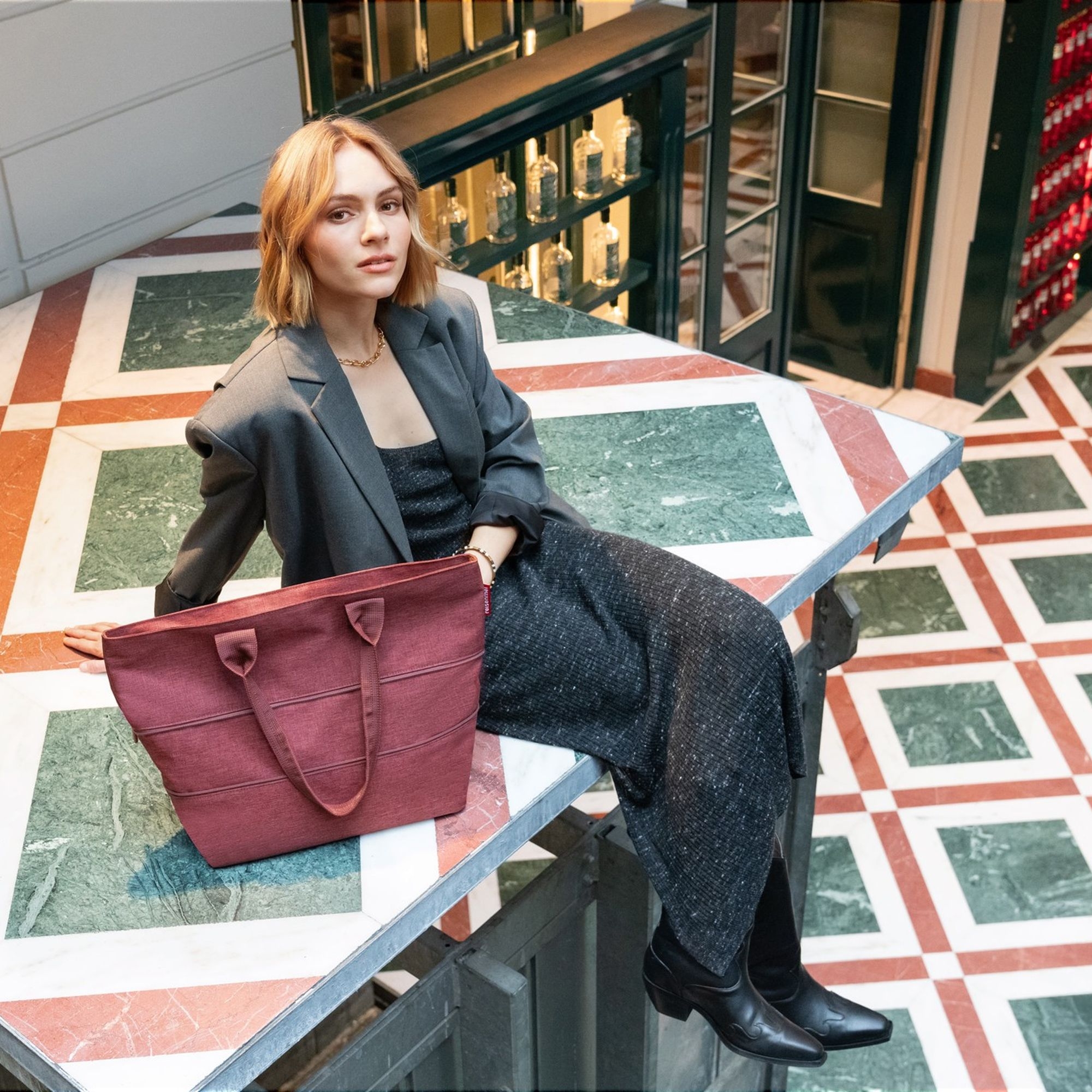 Woman with burgundy shoulder bag on marble table